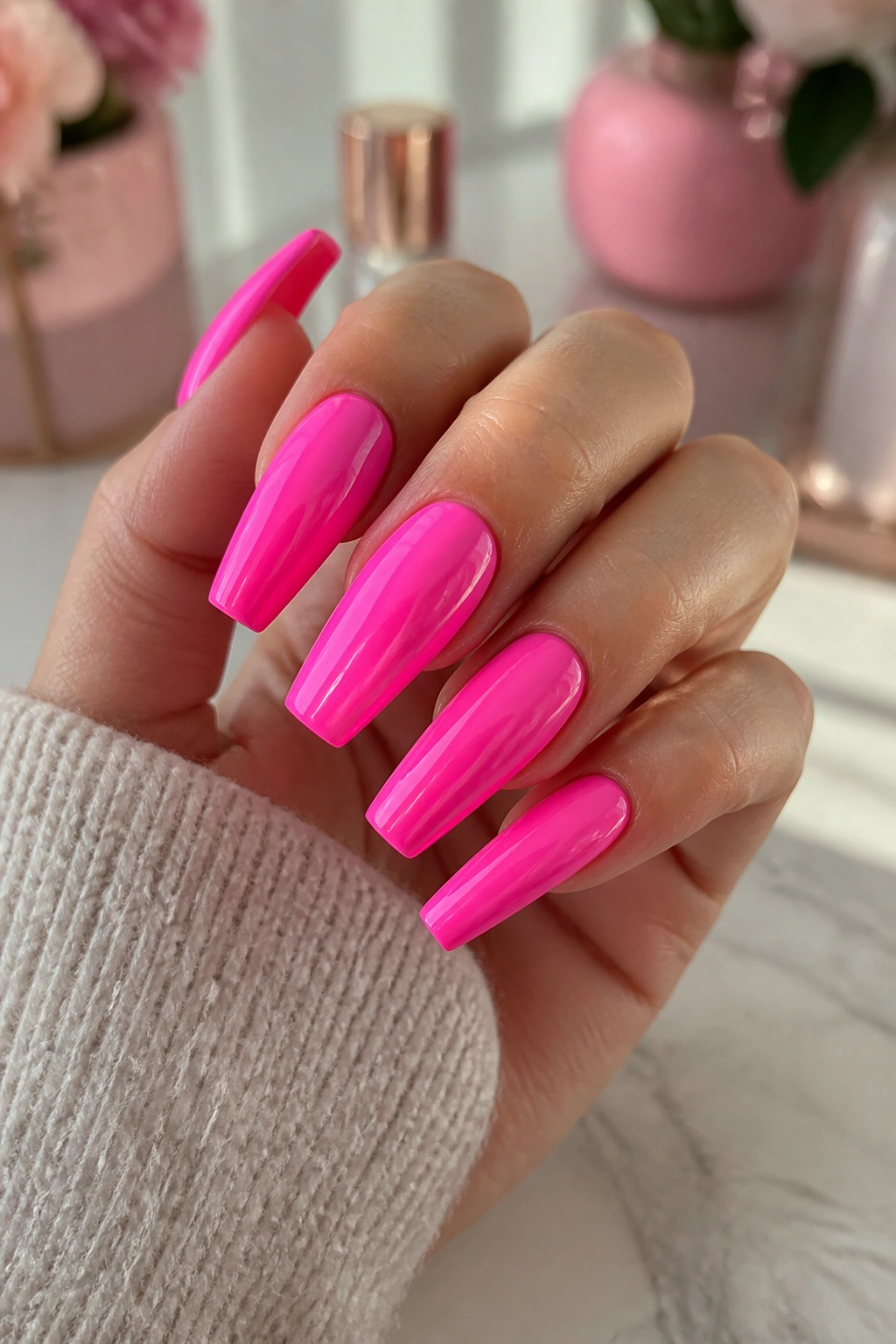 Close-up of bright candy pink full-gloss coffin nails on a hand