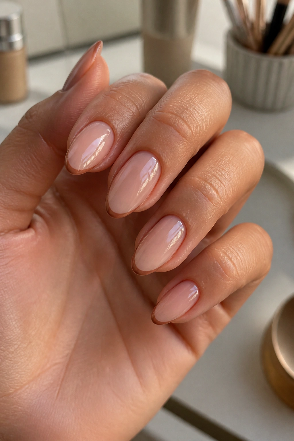 Close-up of almond nails with caramel micro French on sheer nude base