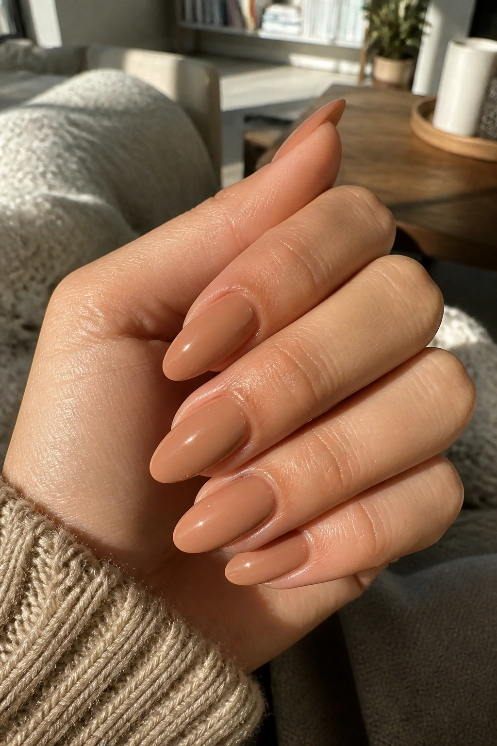 Close-up of hand showing caramel nude almond nails