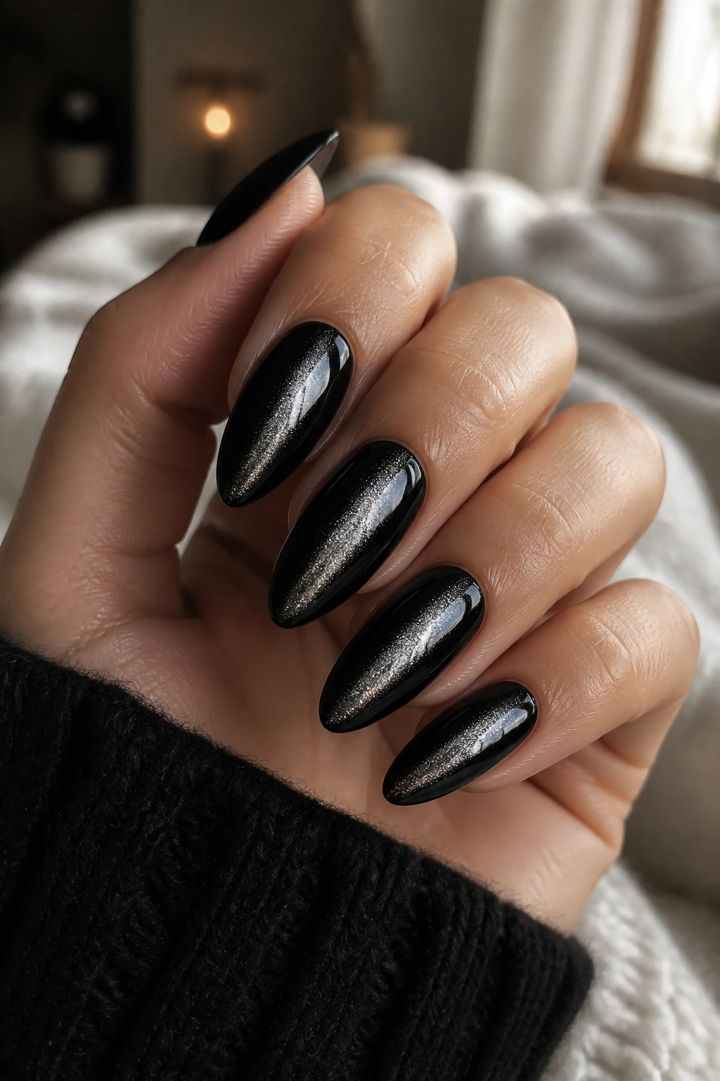 Close-up of velvet cat-eye black almond nails showing shifting shimmer