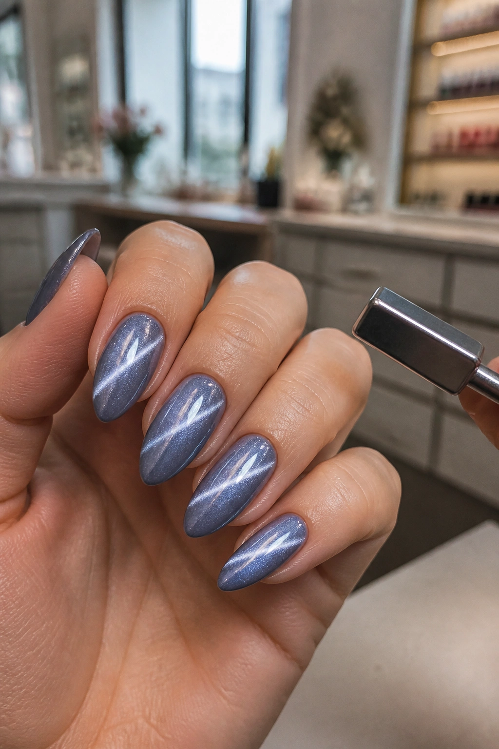 Close-up of almond nails with magnetic cat-eye shimmer in blue