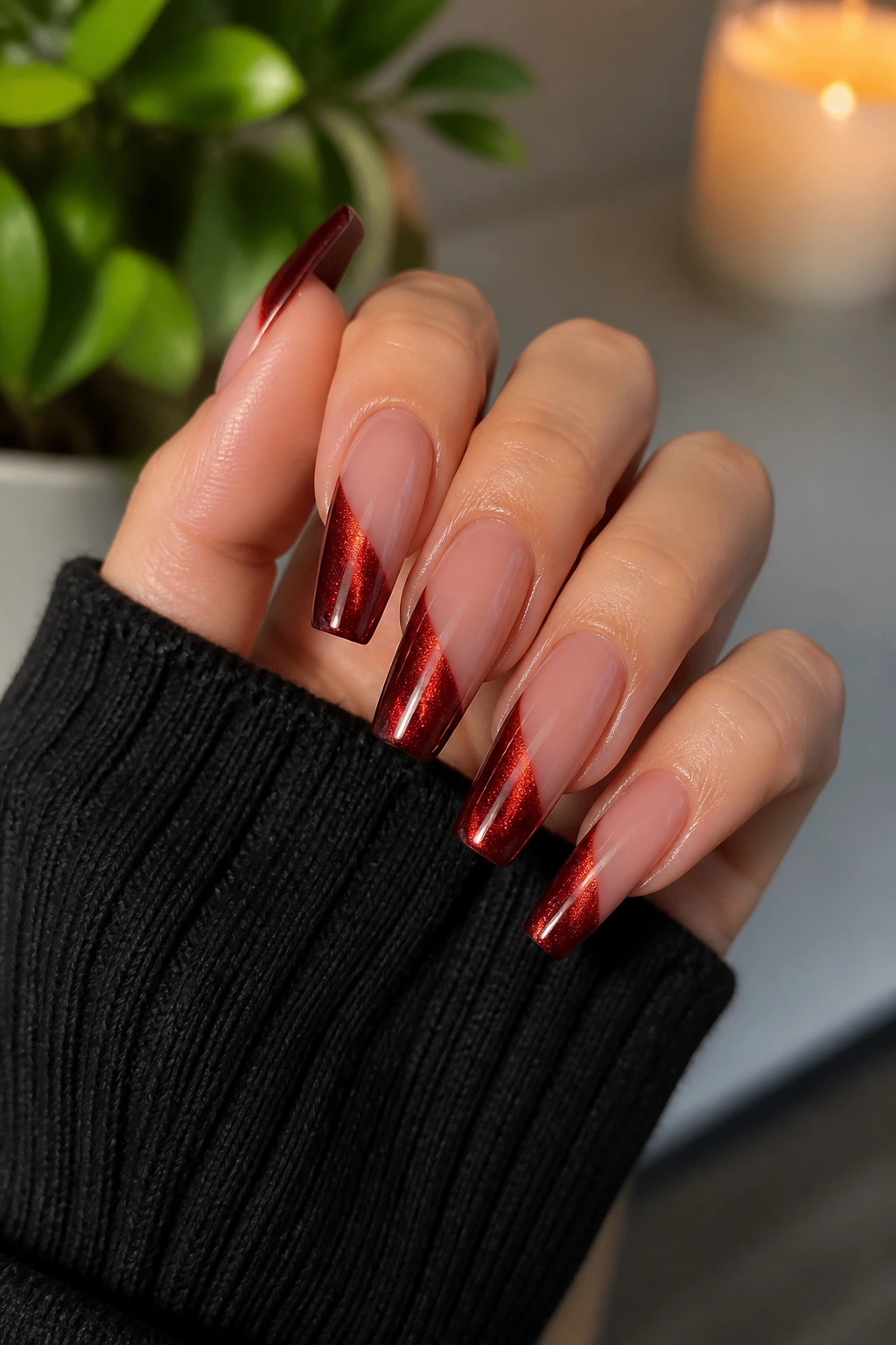 Close-up of a hand showing coffin nails with velvet cat-eye dark red tips catching light.