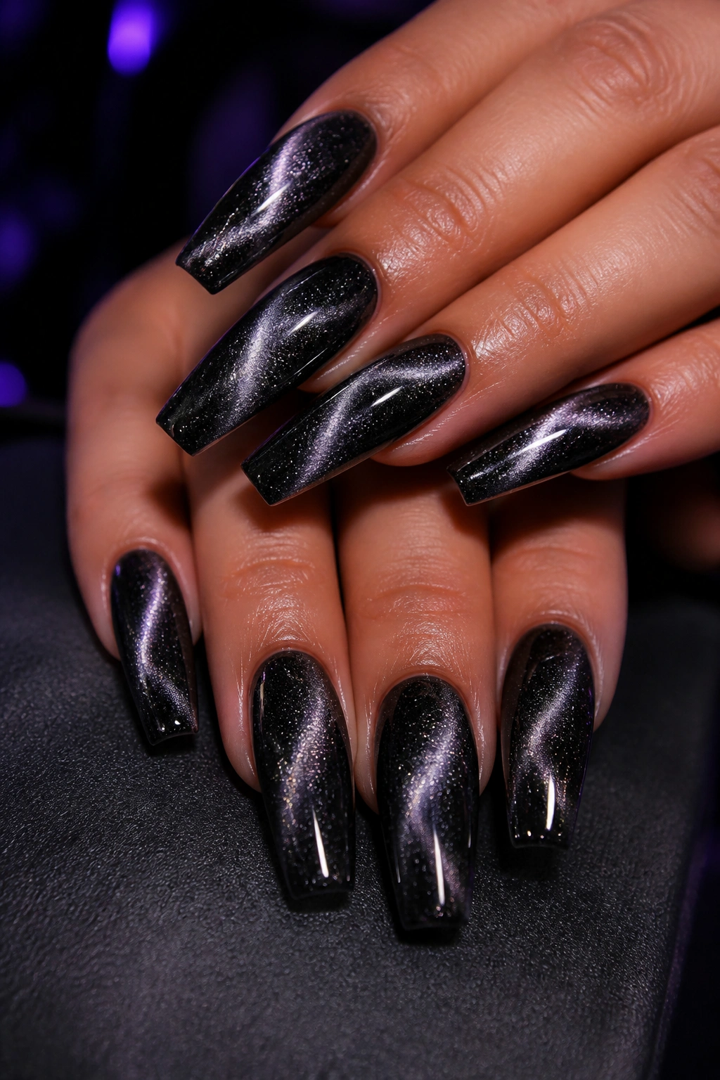 Close-up of velvet cat-eye black glitter coffin nails catching light with diagonal shimmer