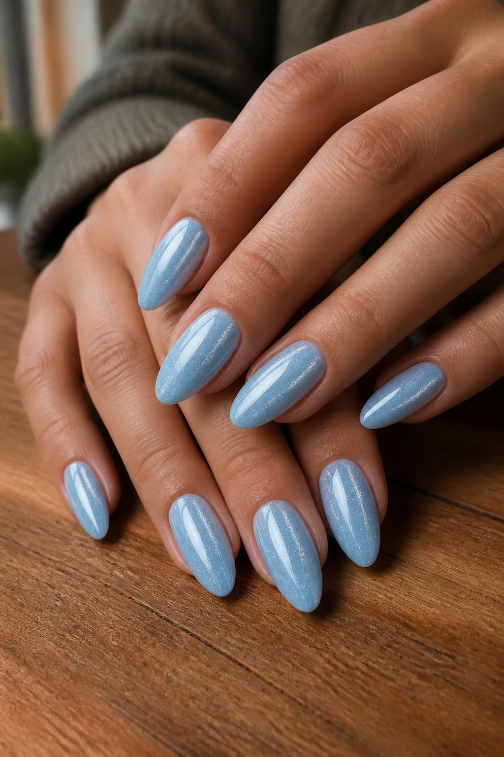 Close-up of velvet cat-eye pastel blue almond nails on real hands