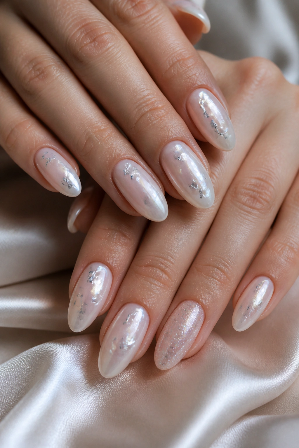 Close-up celestial pearl almond nails with silver flakes