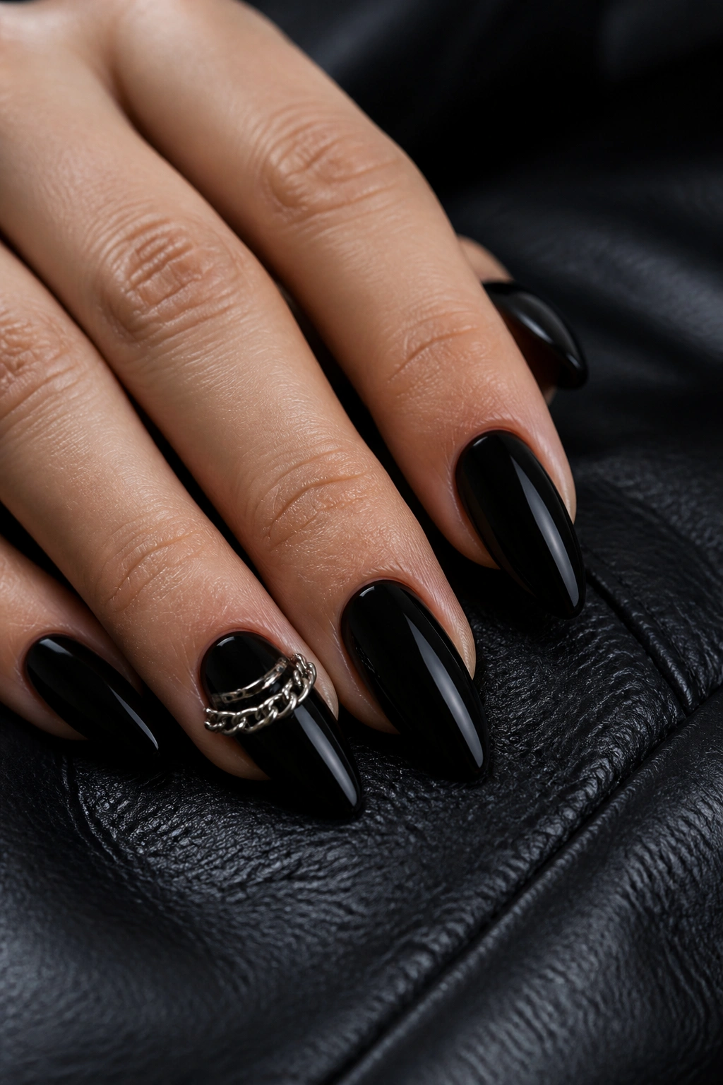 Close-up of almond nails with black base and chain hardware accent