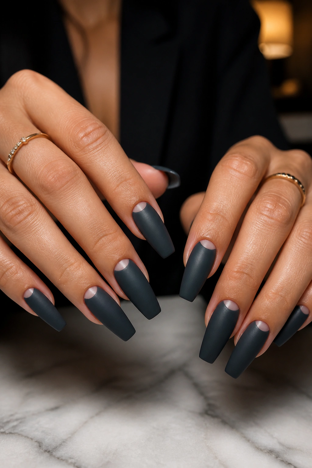 Close-up of charcoal matte coffin nails with negative-space half-moons on a hand
