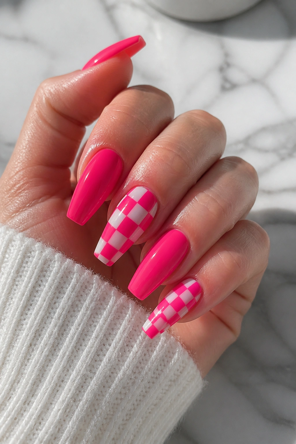 Close-up of checkerboard hot pink coffin nails on a hand