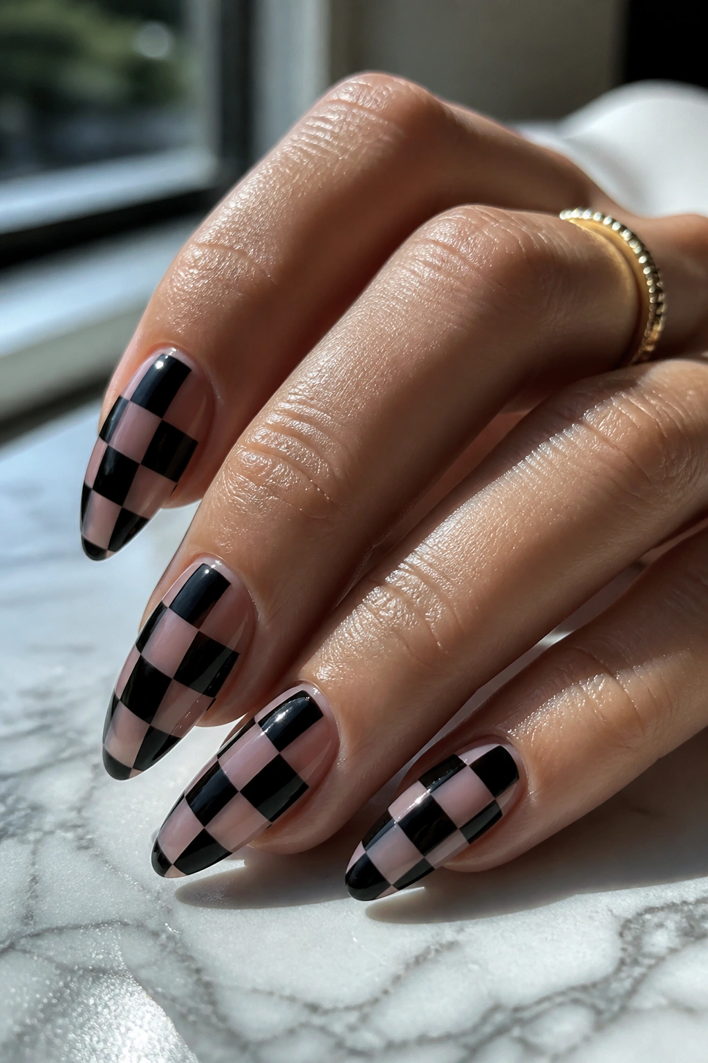 Close-up of almond nails with black and clear checkerboard pattern
