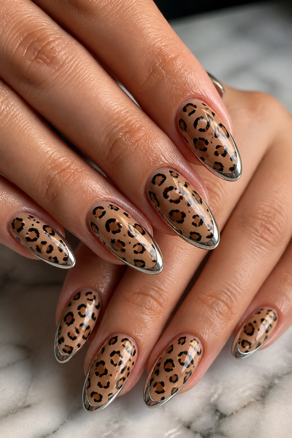 Close-up of almond nails with cheetah print and a slim chrome edge on a real hand