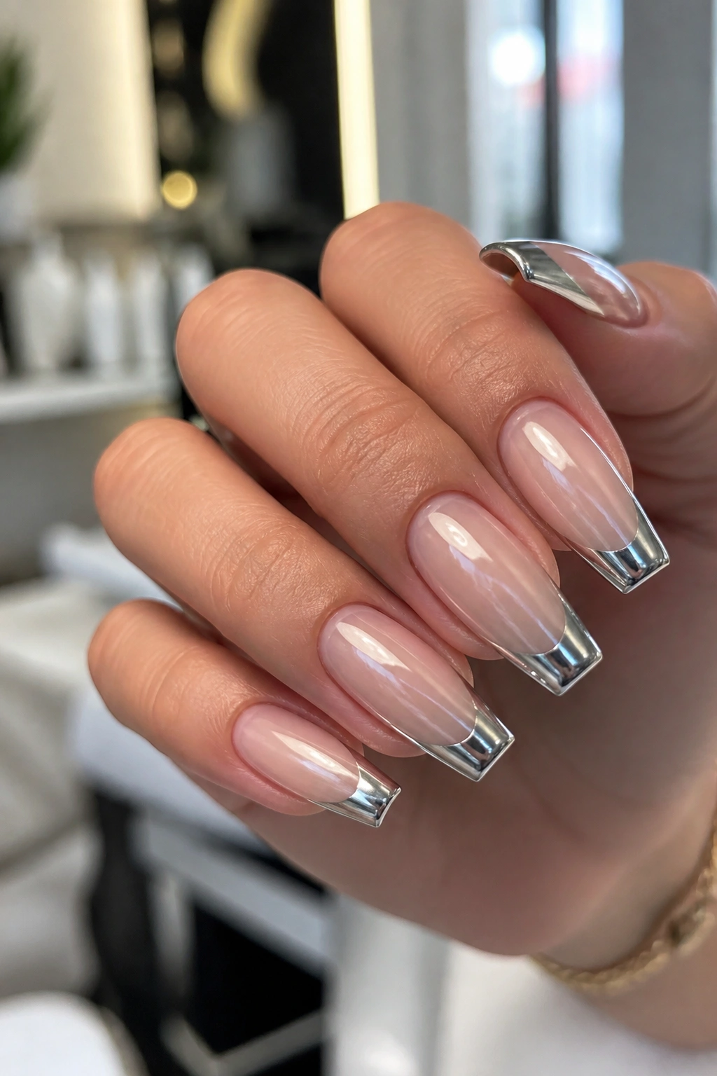 Real hand with chrome French tips over sheer nude base