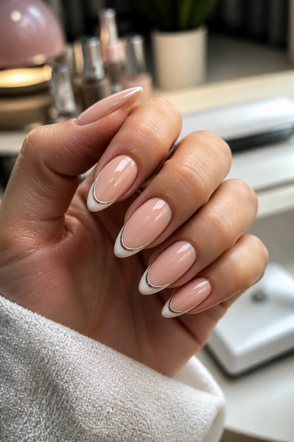 Close-up of almond nails with chrome-lined tips on nude base