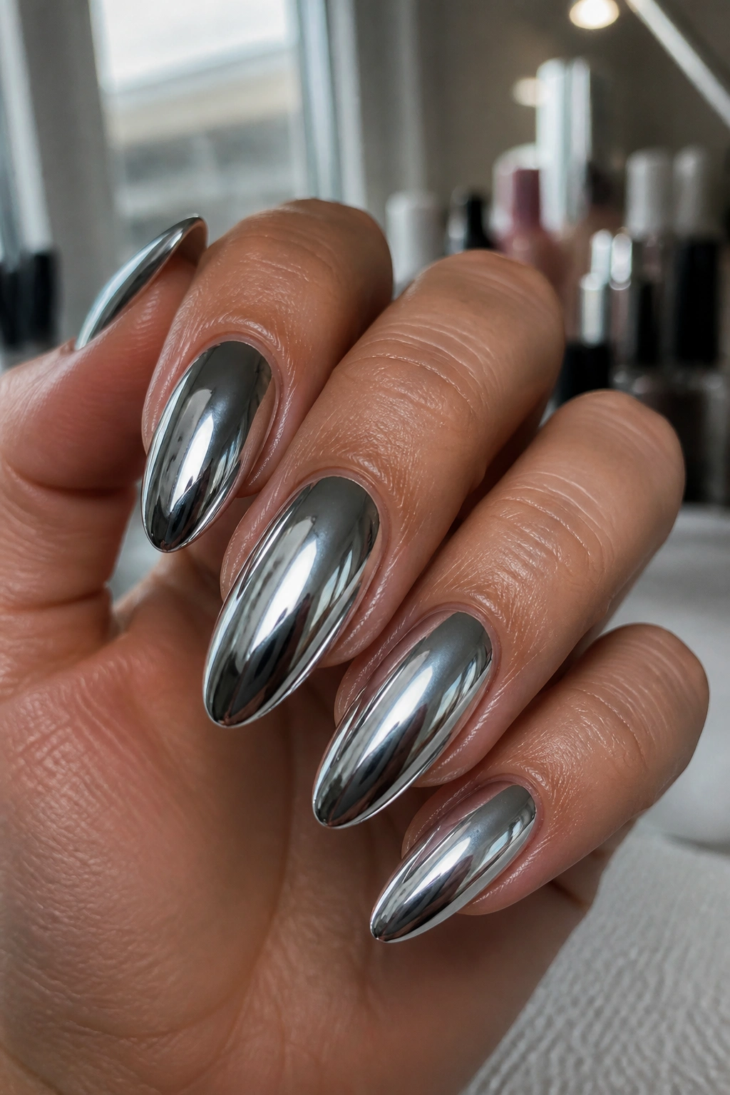 Close-up of almond nails with a full mirror chrome finish on a real hand