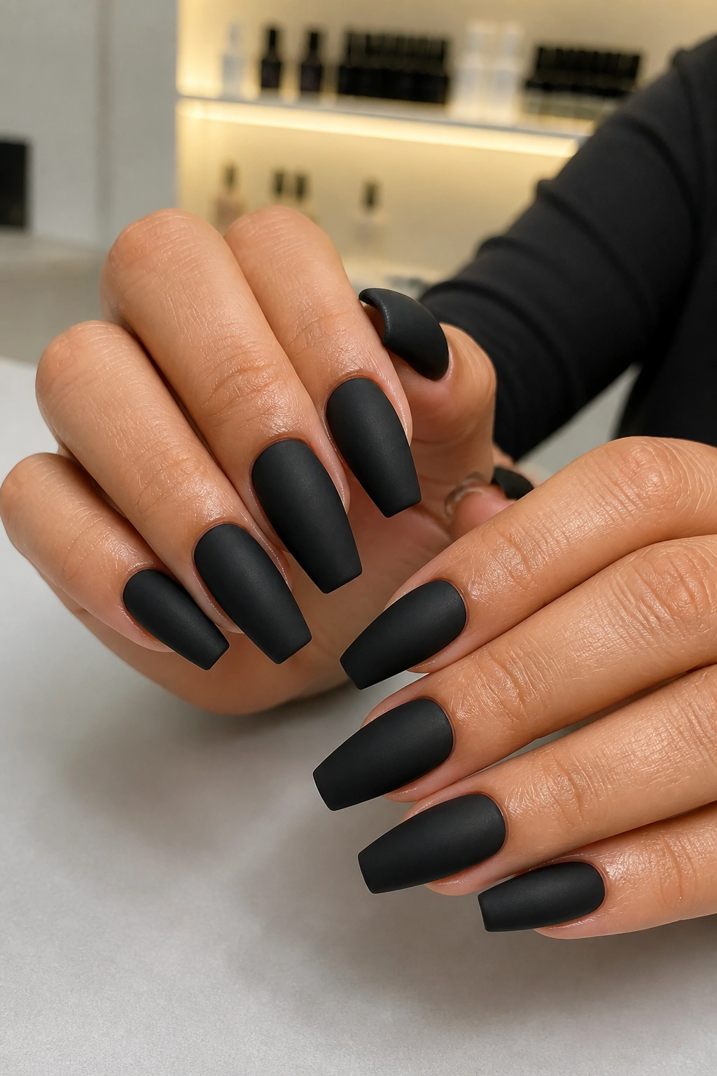 Close-up of classic full-coverage matte black coffin nails on a real hand.