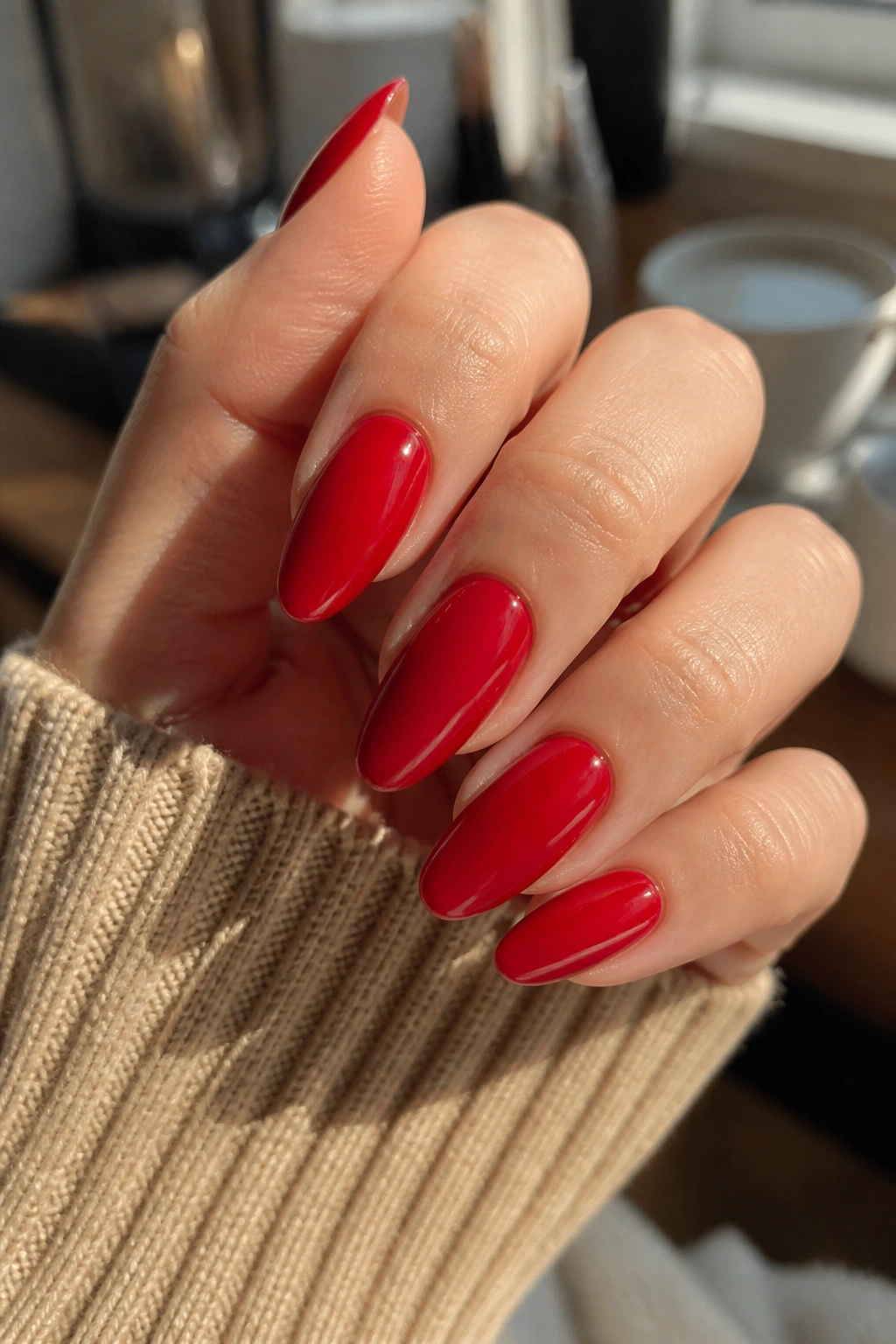 Close-up of clean glossy red almond nails on a real hand