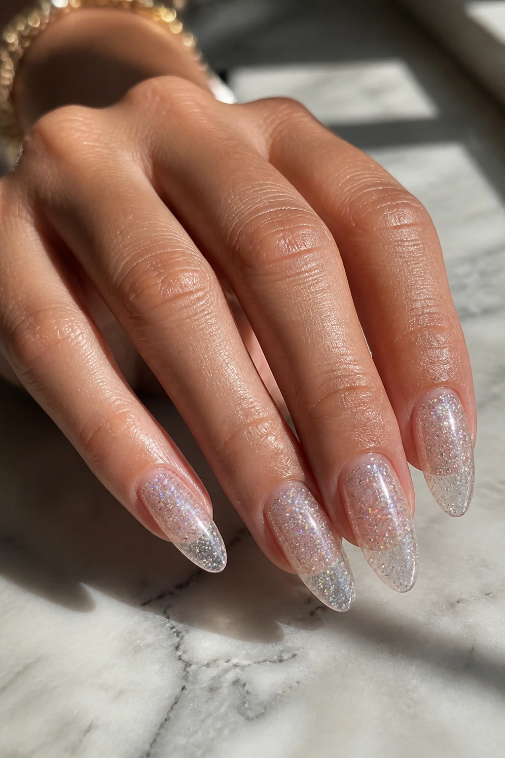 Close-up of almond nails with clear glitter glass design on a real hand