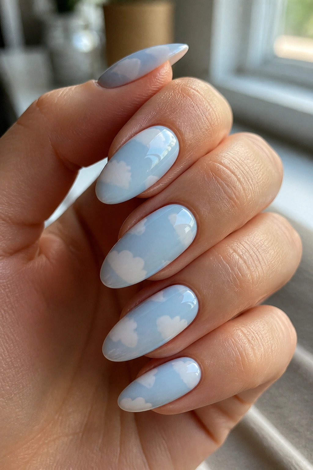 Close-up of almond nails with light blue base and white cloud nails on a real hand
