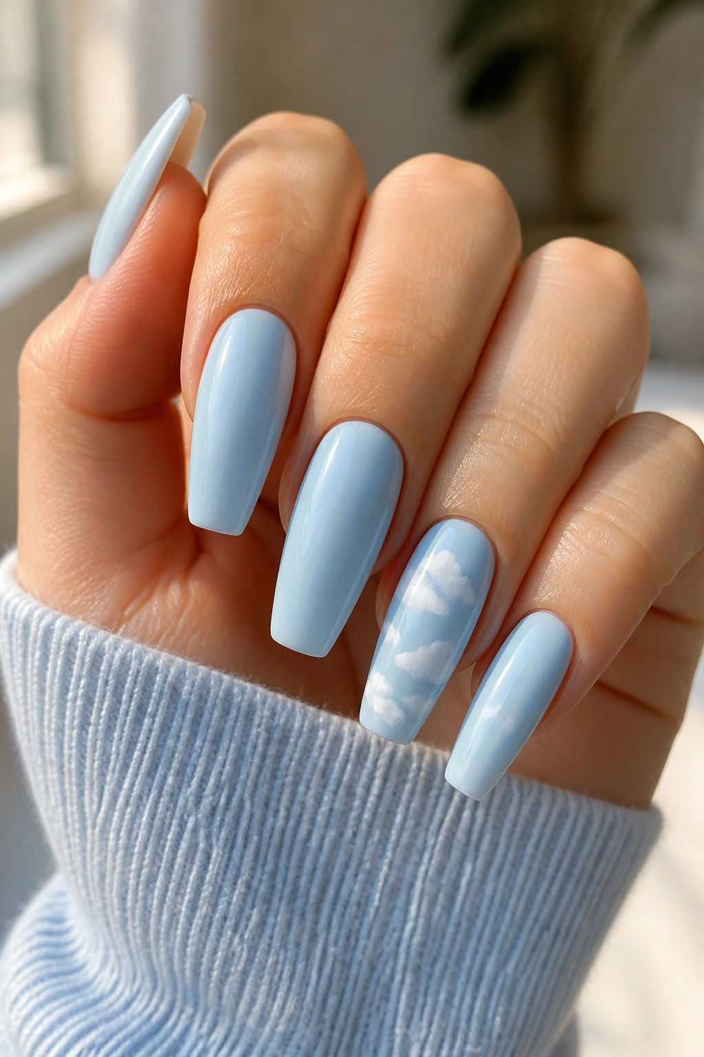 Close-up of real hand with light blue coffin nails featuring white cloud accents on accent nails