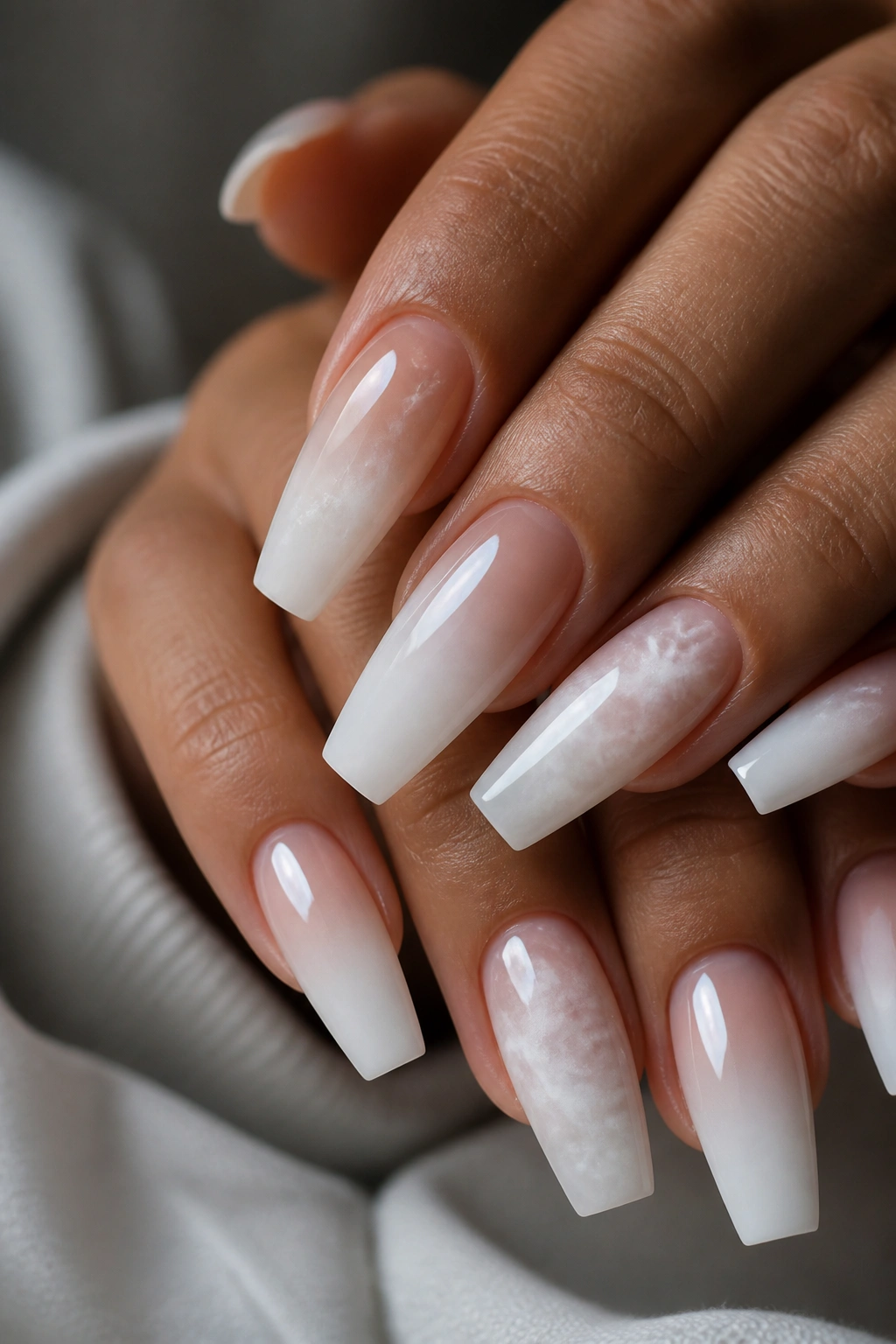 Close-up of coffin nails with cloud-like white ombre and soft swirls on a real hand