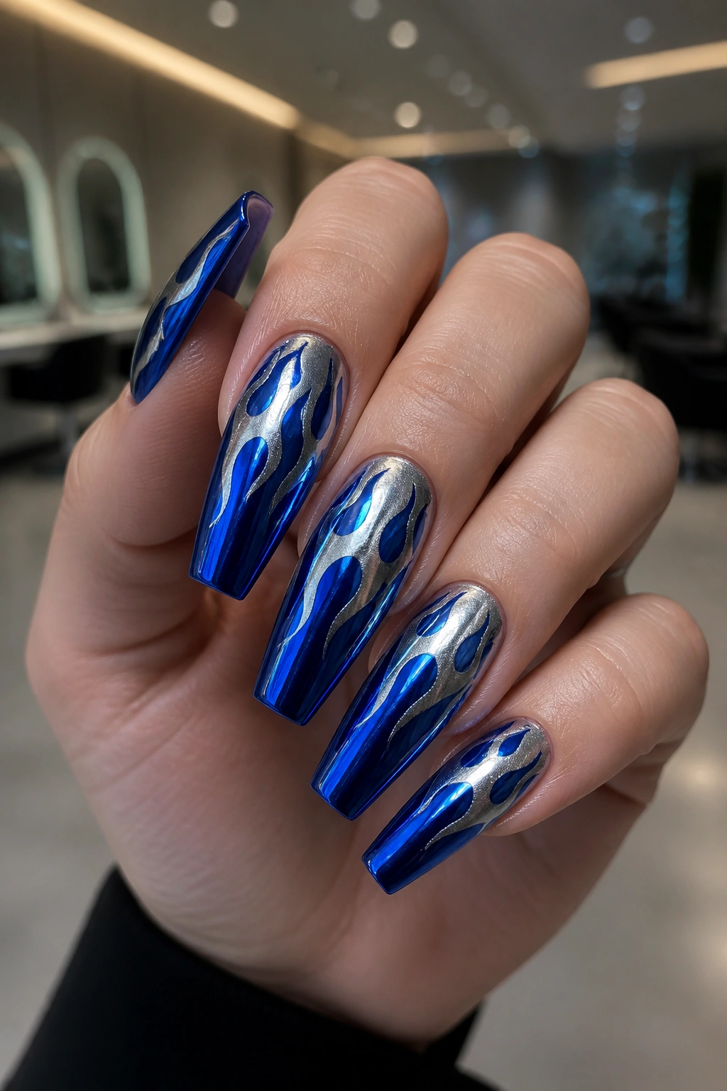Close-up of cobalt flame chrome nails with sharp coffin edges on a real hand