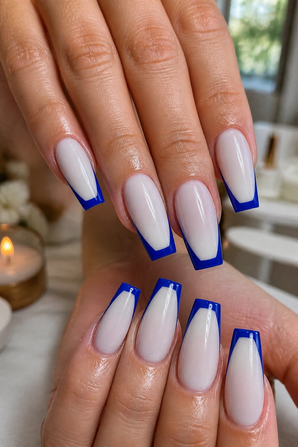 Close-up of hands showing coffin nails with milky white base and cobalt tips