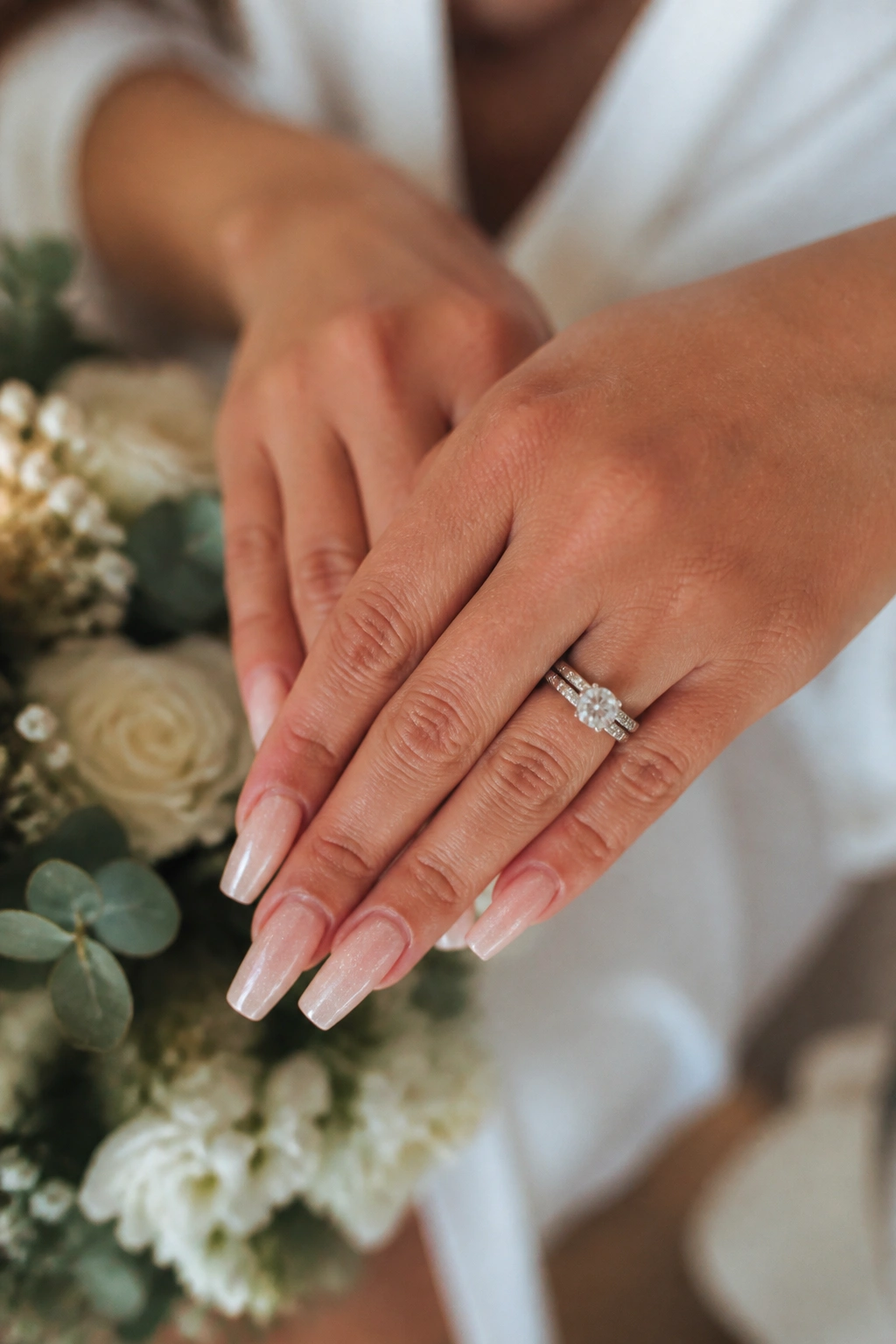 Close-up of hands with coffin nails in a medium length showing tapered edges in a bridal prep setting
