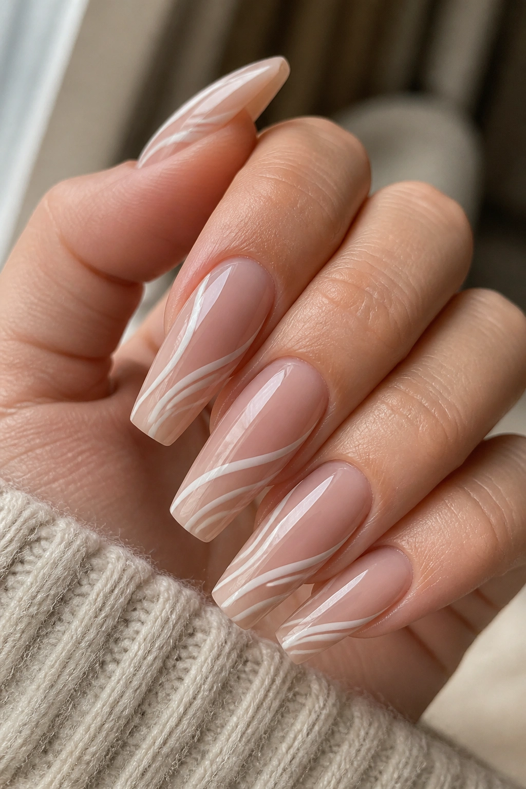 Close-up of medium coffin nails with side-swept white swirls on a neutral base