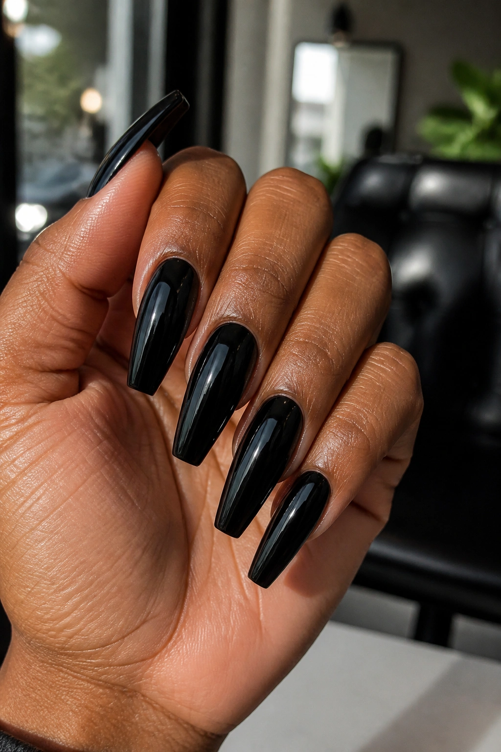Close-up of real hand with tapered coffin nails in black polish highlighting shape