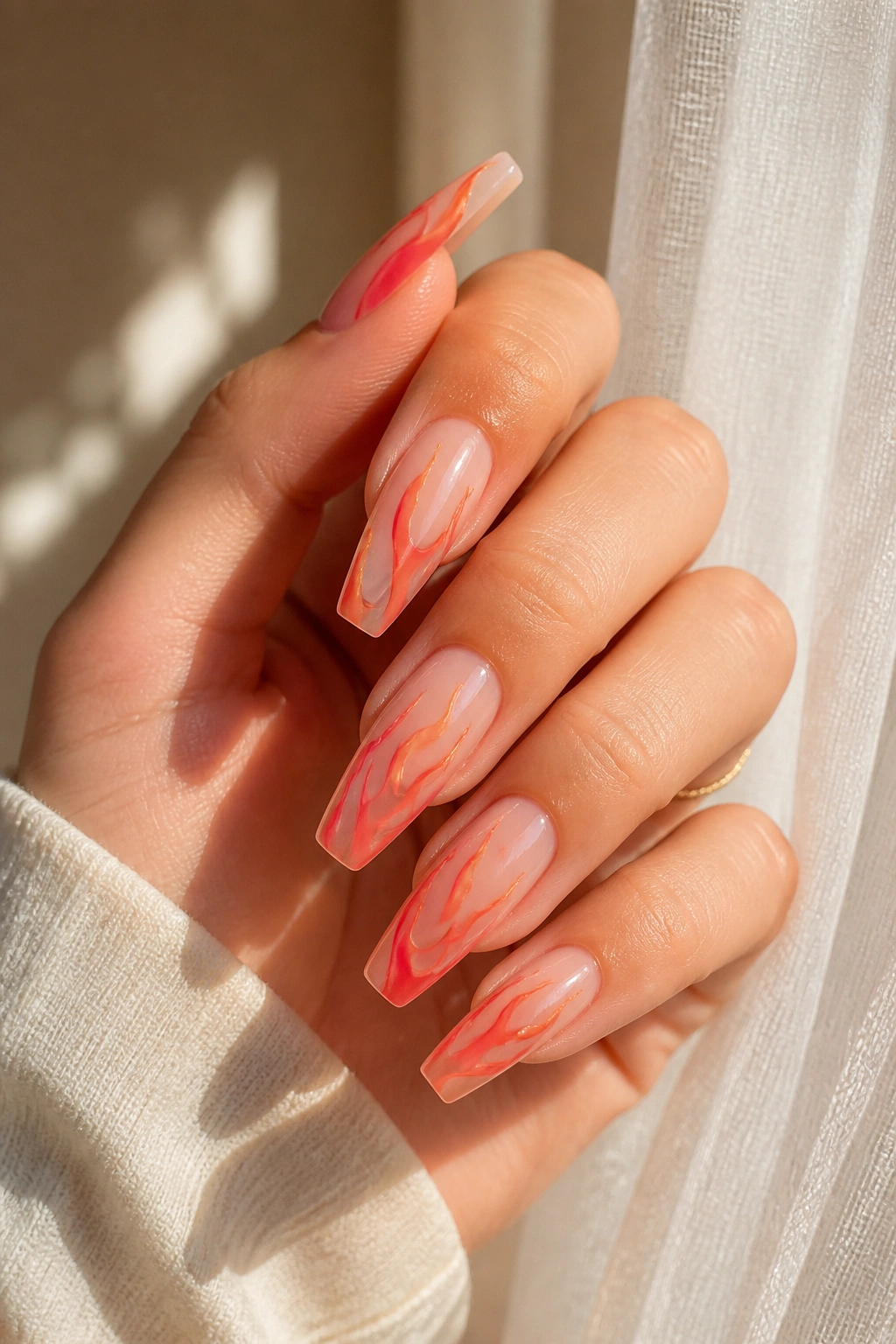 Close-up of coral flame nails on a sheer base