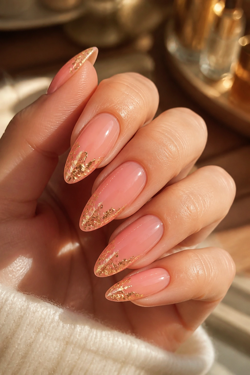 Close-up of coral pink nails with gold foil accents