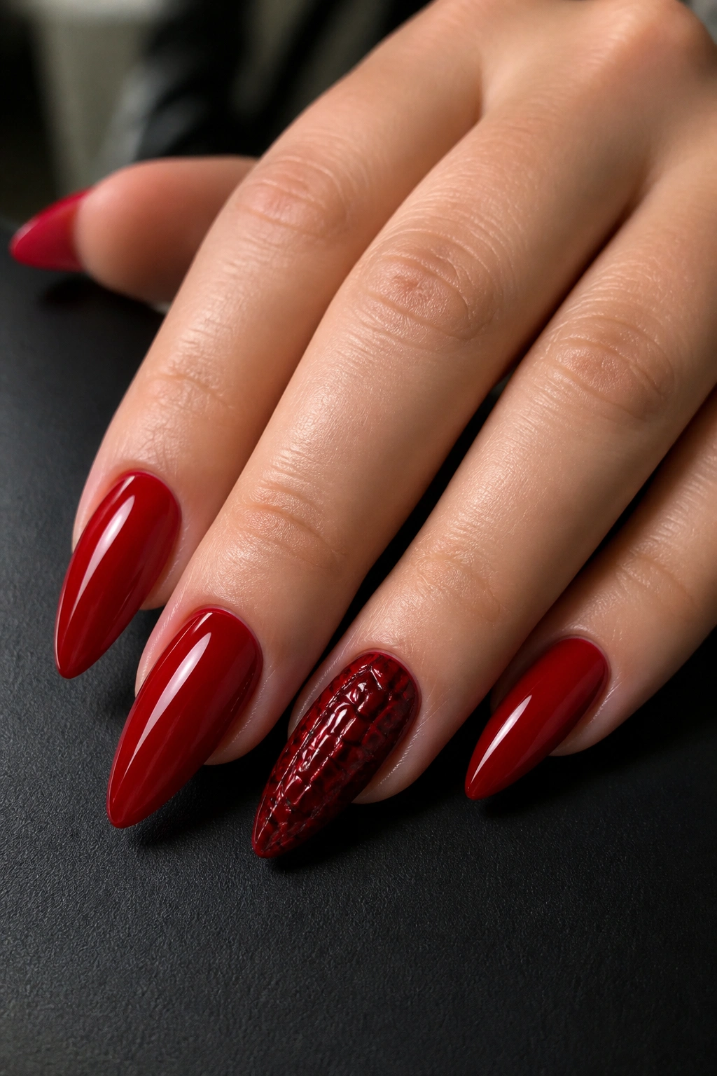 Close-up of croc-textured burgundy accent nail on a long almond manicure