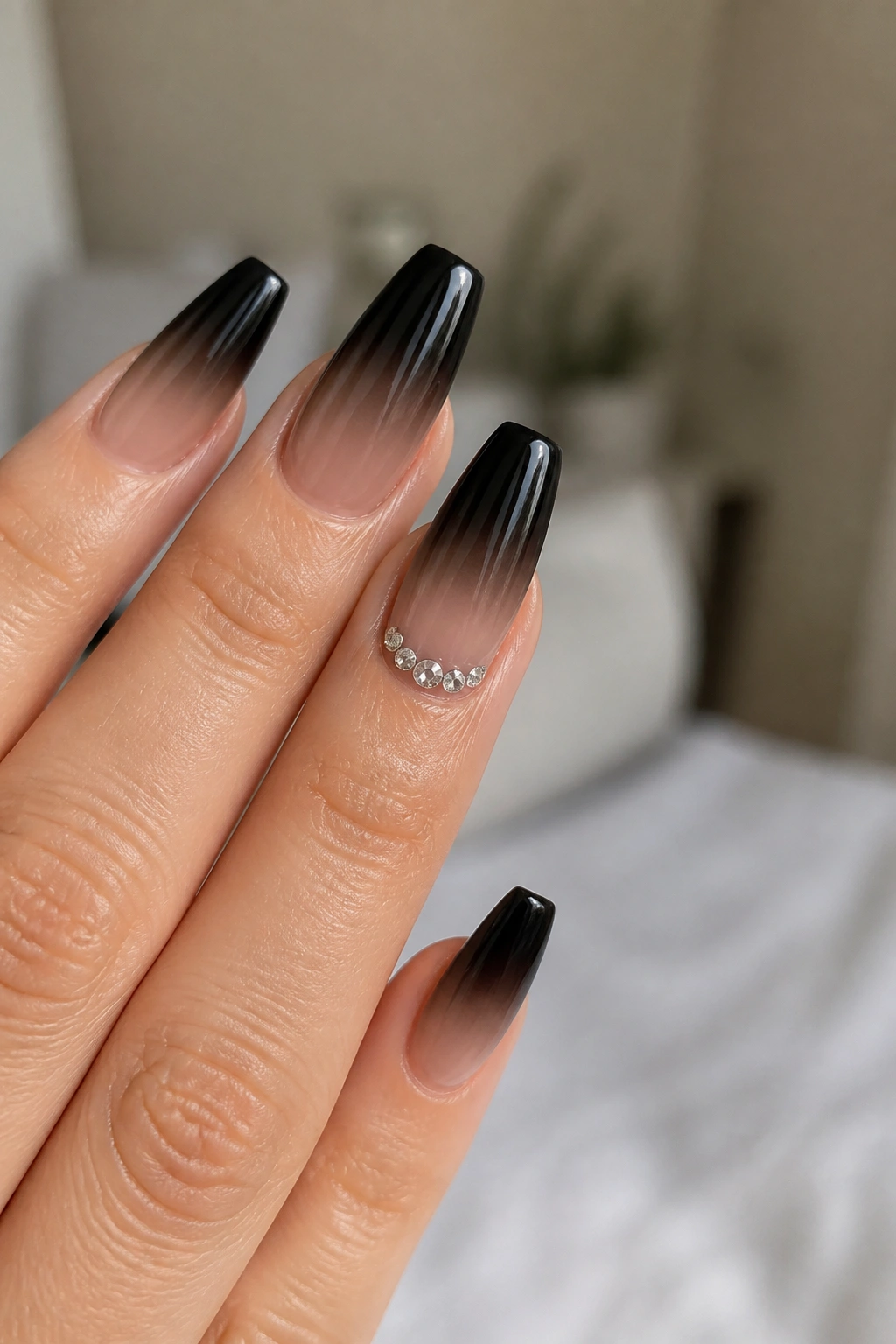 Close-up of crystal cuticle arc with black ombre nails on ring finger.