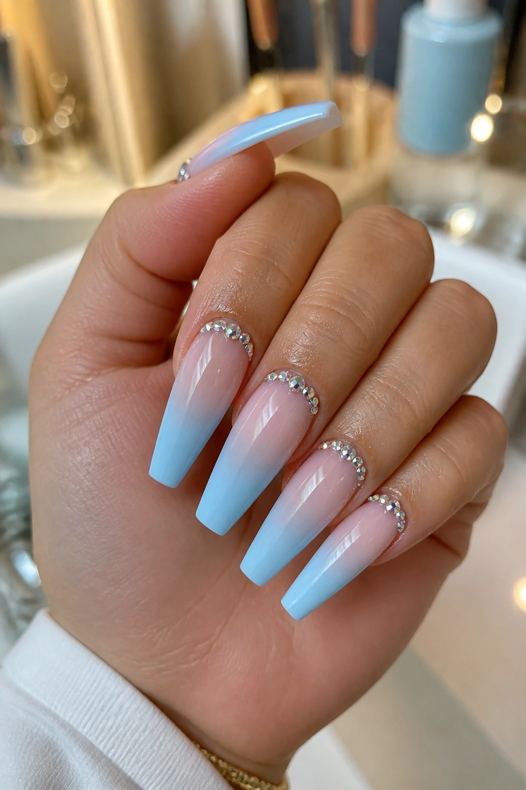 Close-up of cuticle-crystal light blue ombre coffin nails on a real hand in a salon