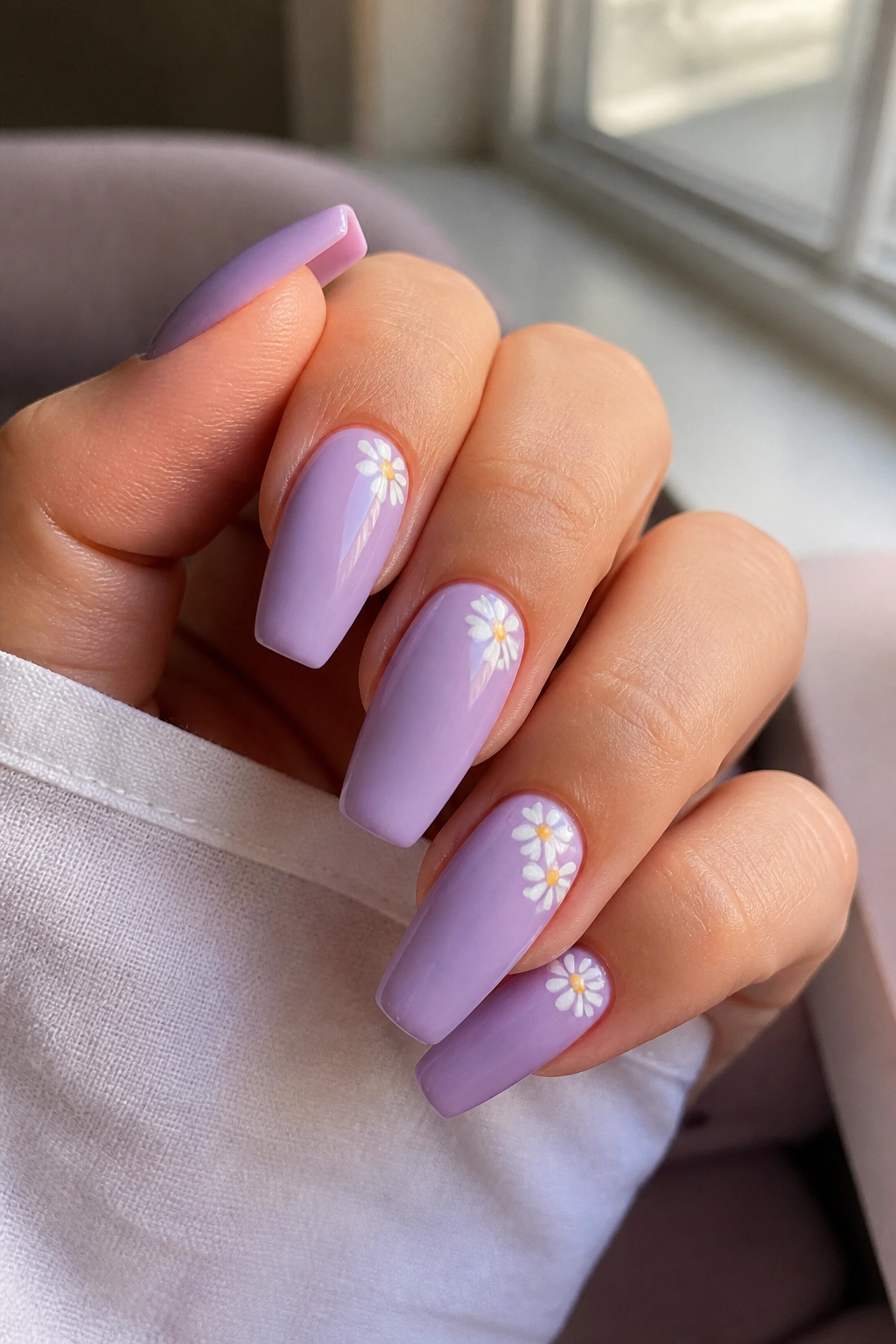 Nails with tiny white daisies on pastel lavender base on a real hand
