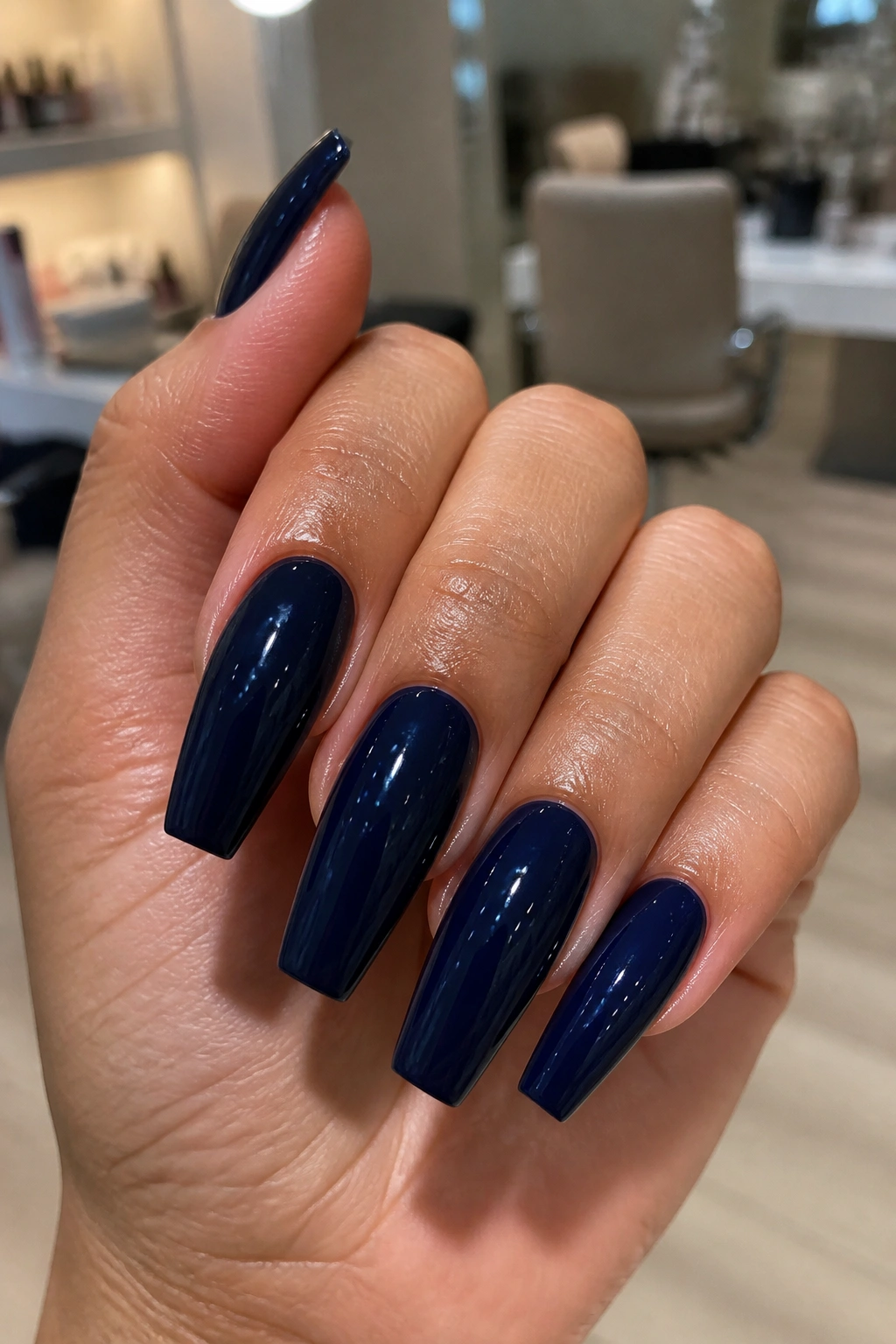 Close-up of a hand with coffin nails painted glossy dark blue navy