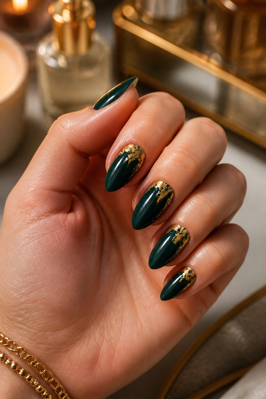 Close-up of a real hand with dark green almond nails and gold foil accents