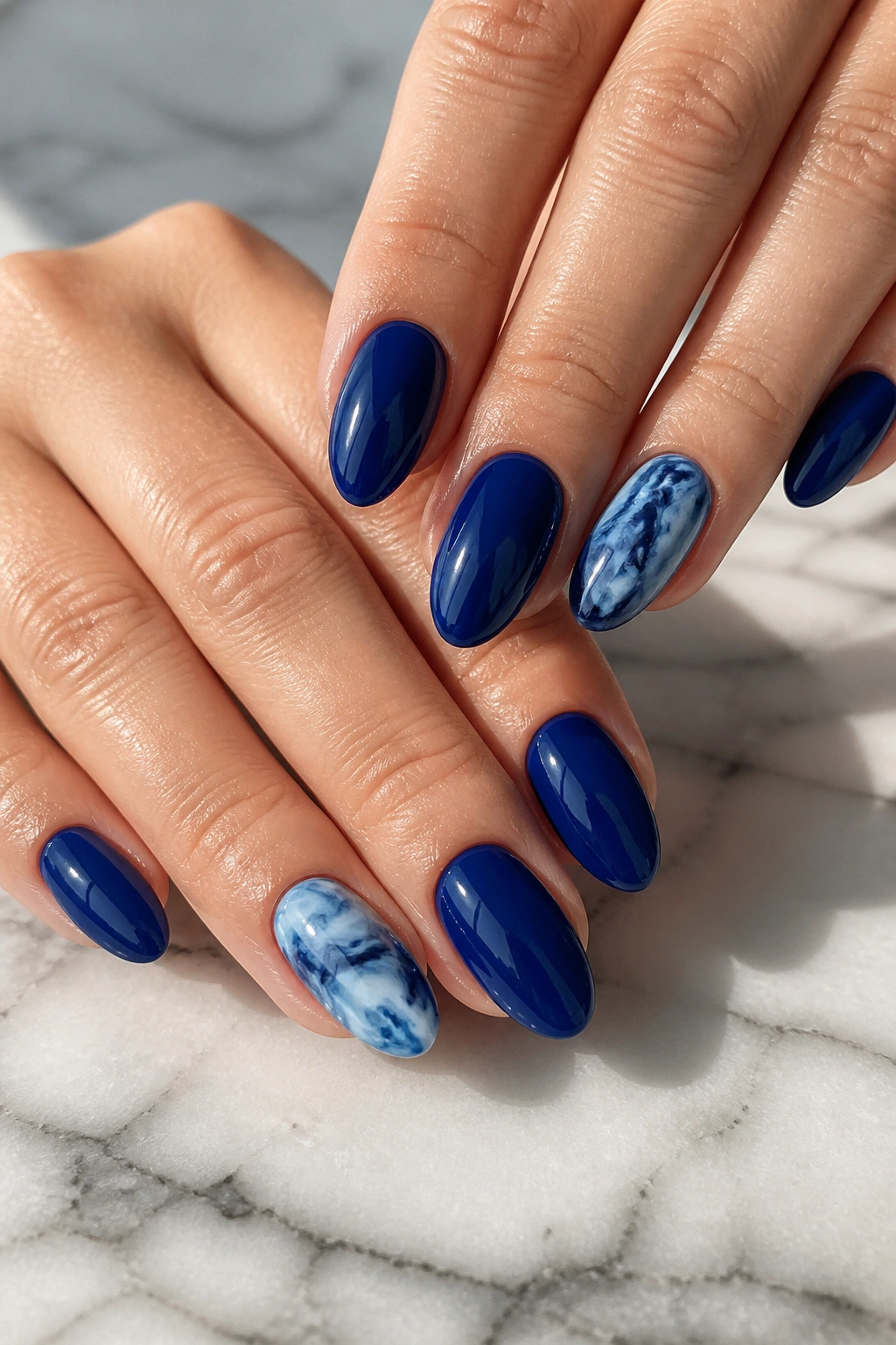 Almond nails with deep blue marble accent on a real hand