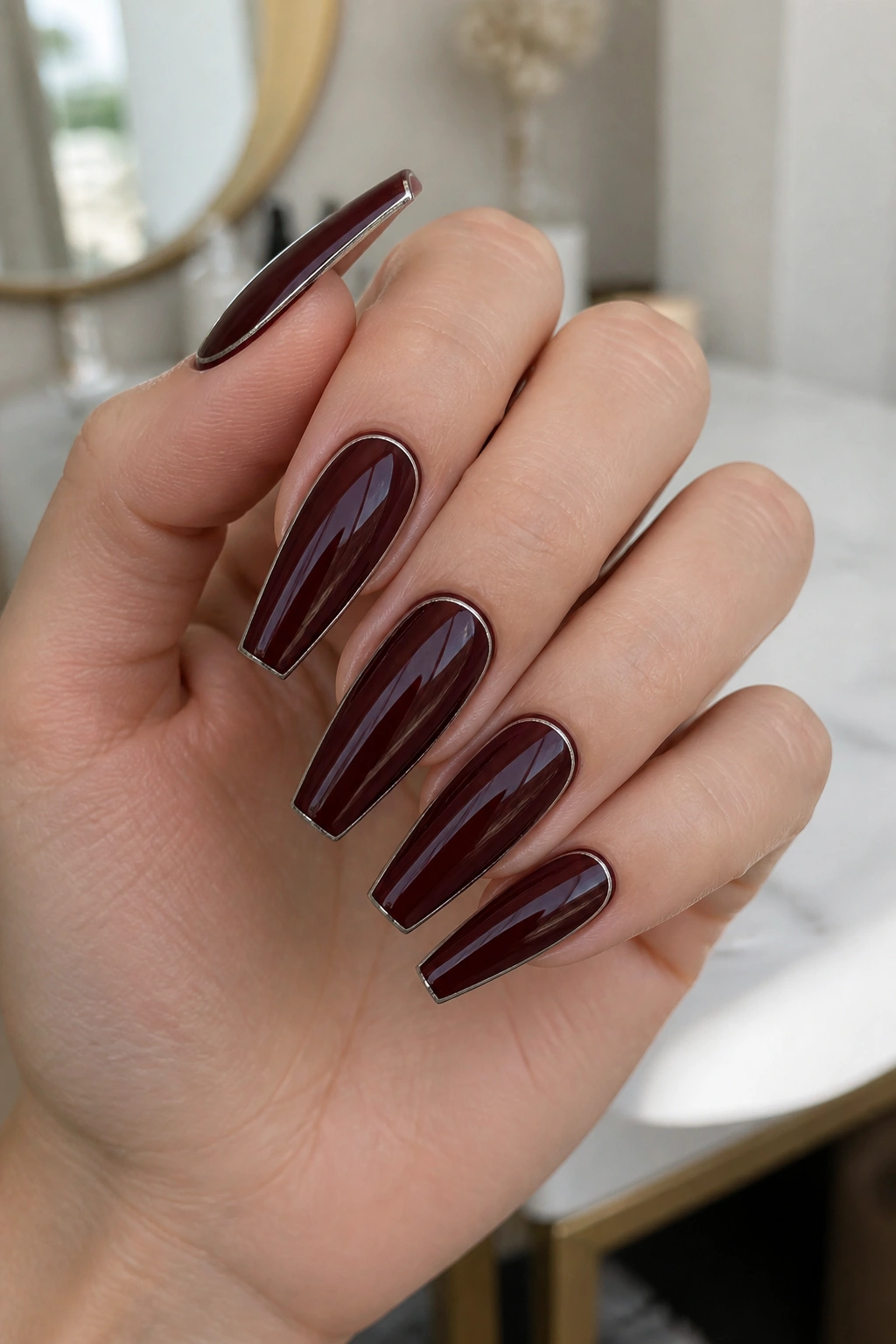 Close-up of deep burgundy coffin nails with silver outline on real hand
