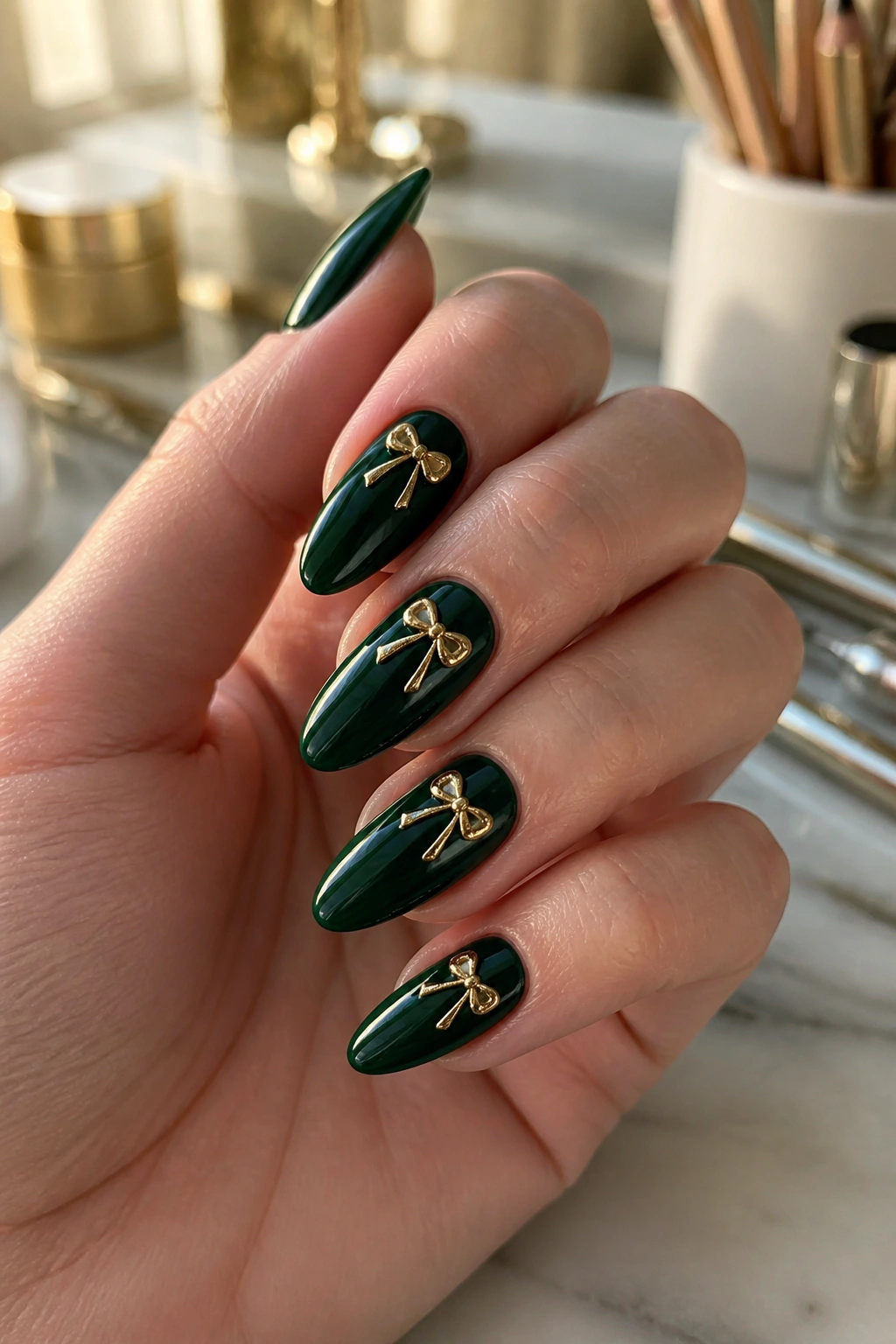 Close-up of deep green almond nails with ivory and gold bows on a real hand at a salon vanity