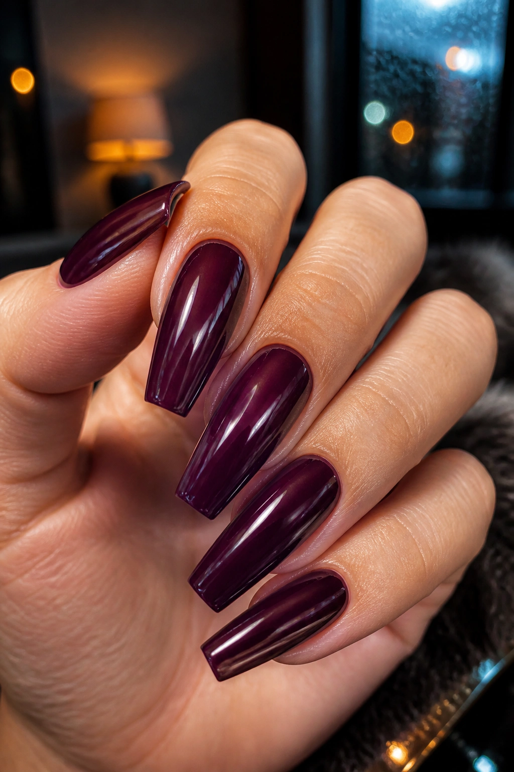 Close-up of deep plum coffin nails with glass shine on a real hand.
