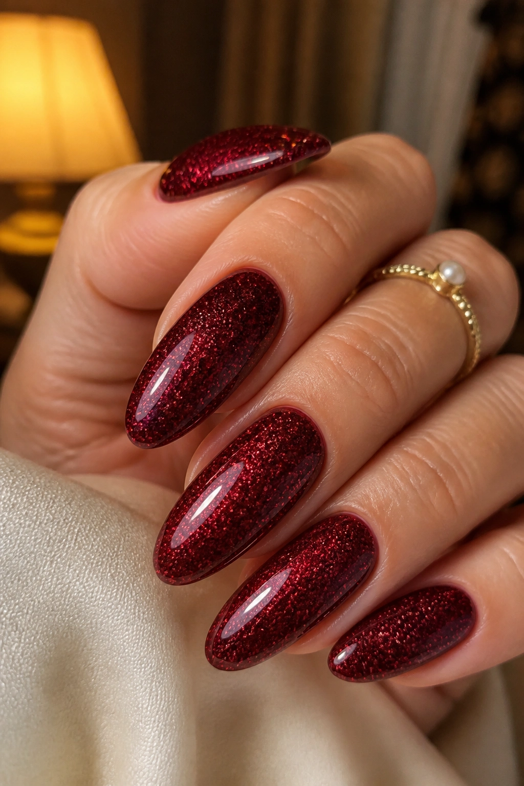 Almond nails with deep red velvet glitter on a dark cream base