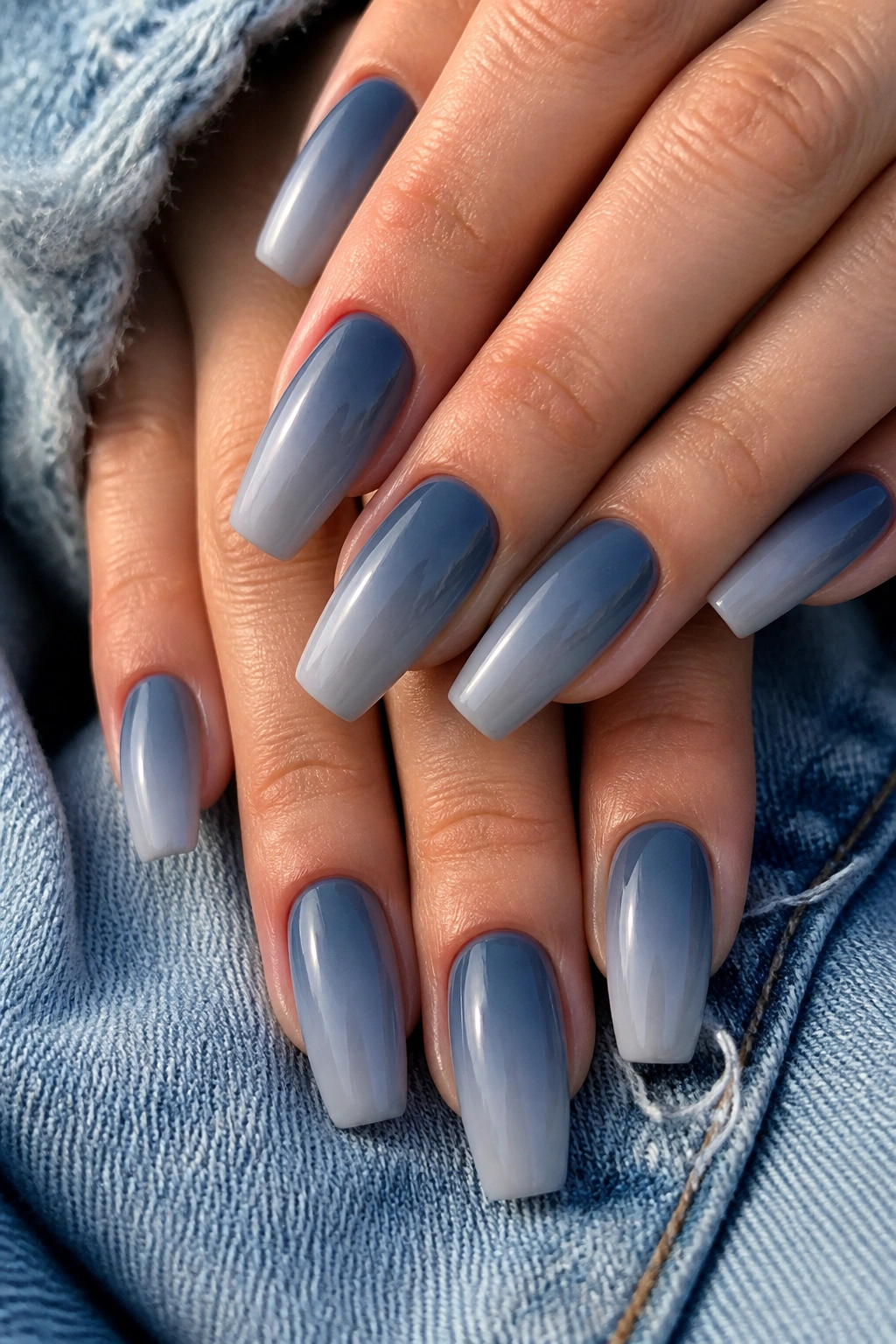 Close-up of medium coffin nails fading from denim blue to soft gray with satin finish
