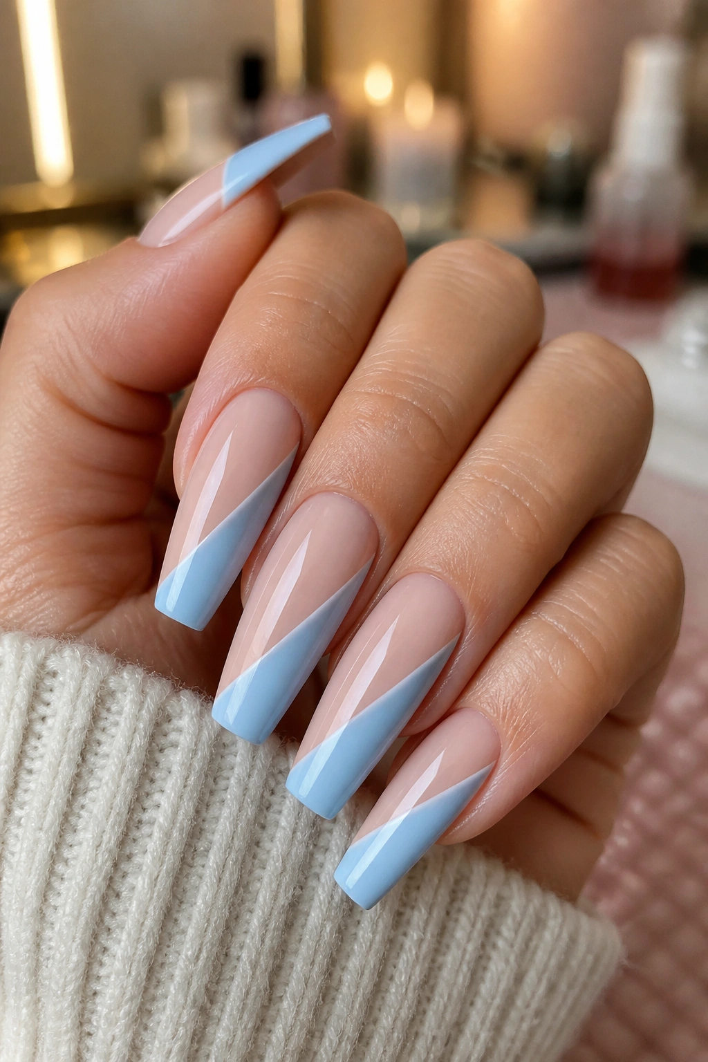 Nude and baby blue diagonal color-block coffin nails on a real hand