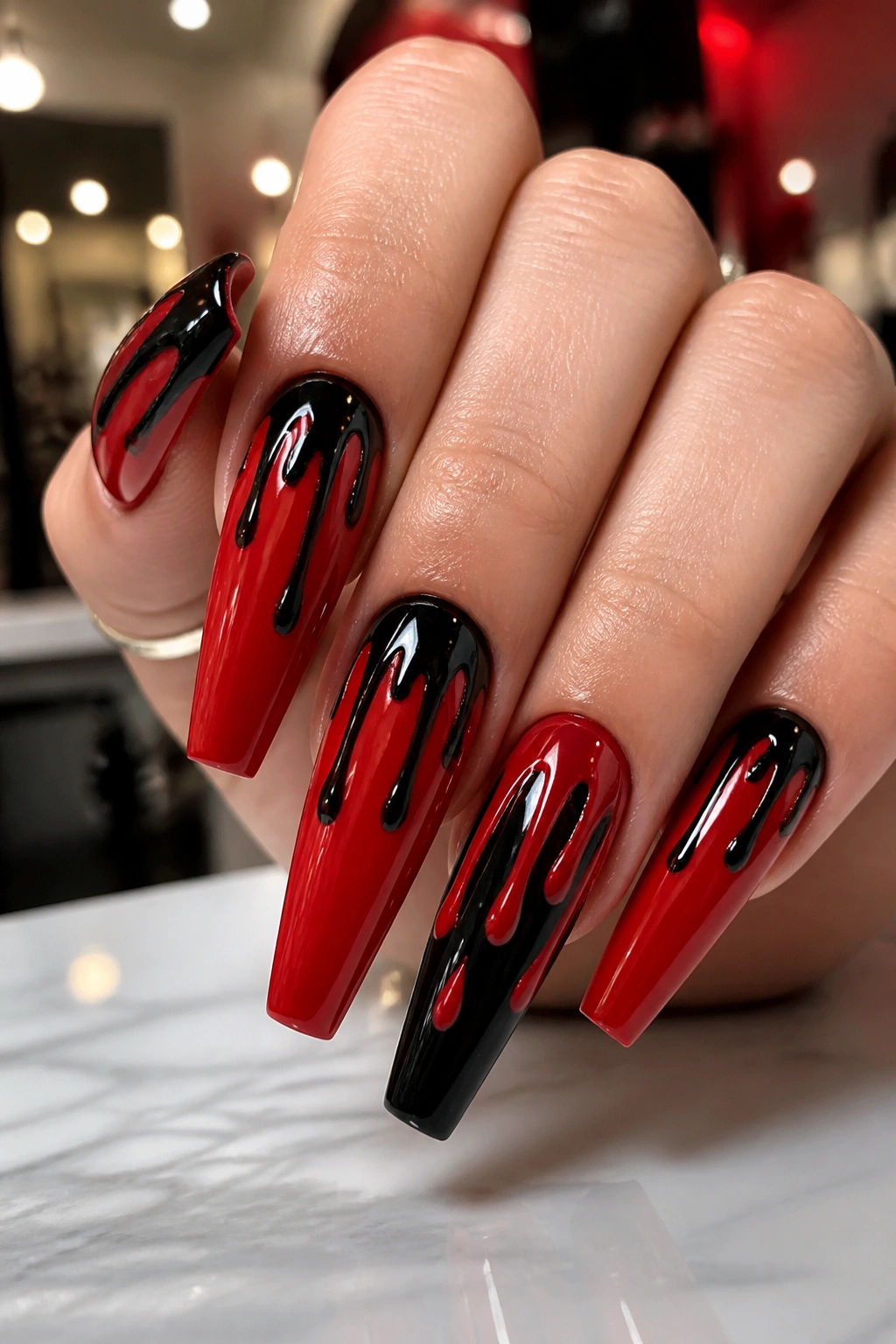 Close-up of black drip nail art on candy-apple red coffin nails on a real hand