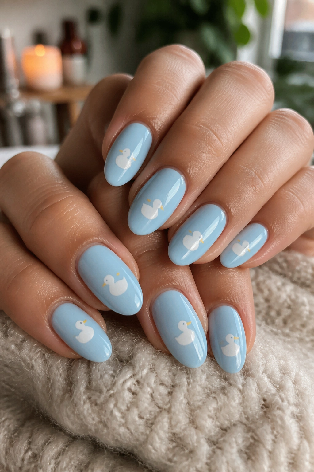 Close-up of real person's hands with baby blue duck nail art, warm window light