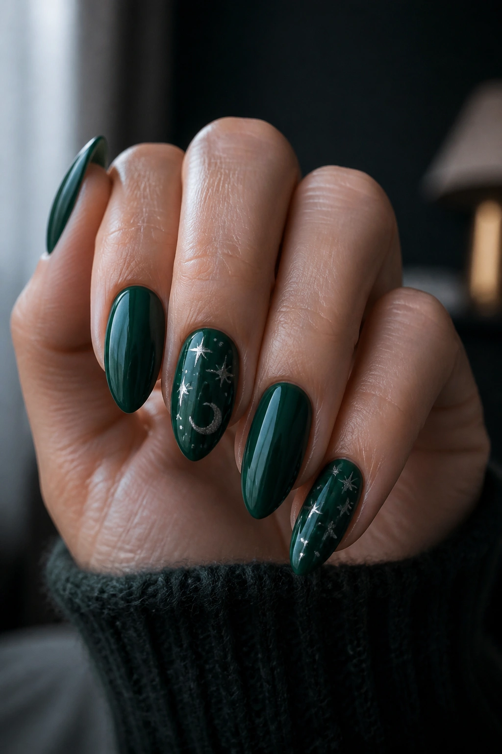 Close-up of a real hand with emerald almond nails and subtle celestial accents.