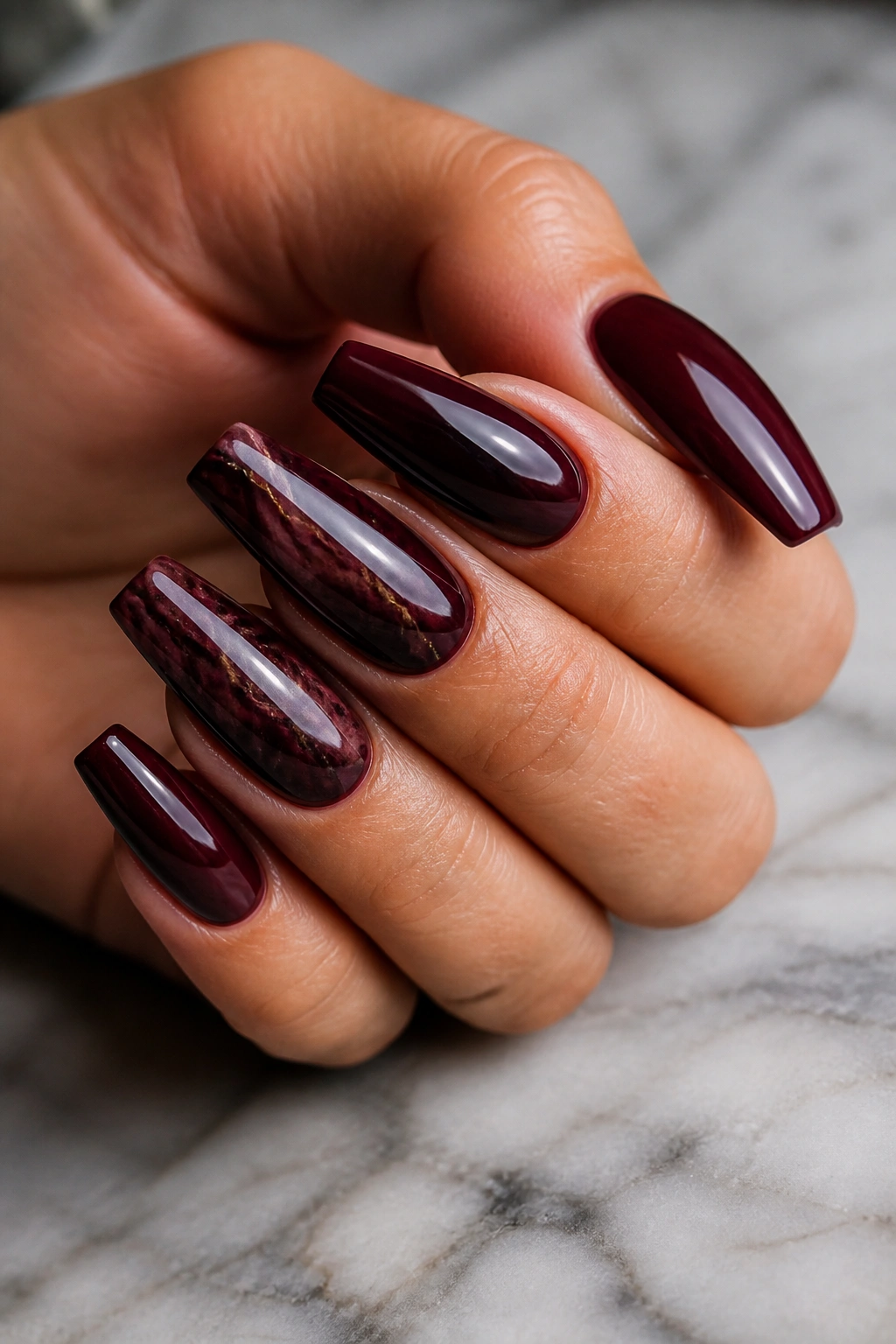 Espresso-maroon marble manicure with thin veining on coffin nails