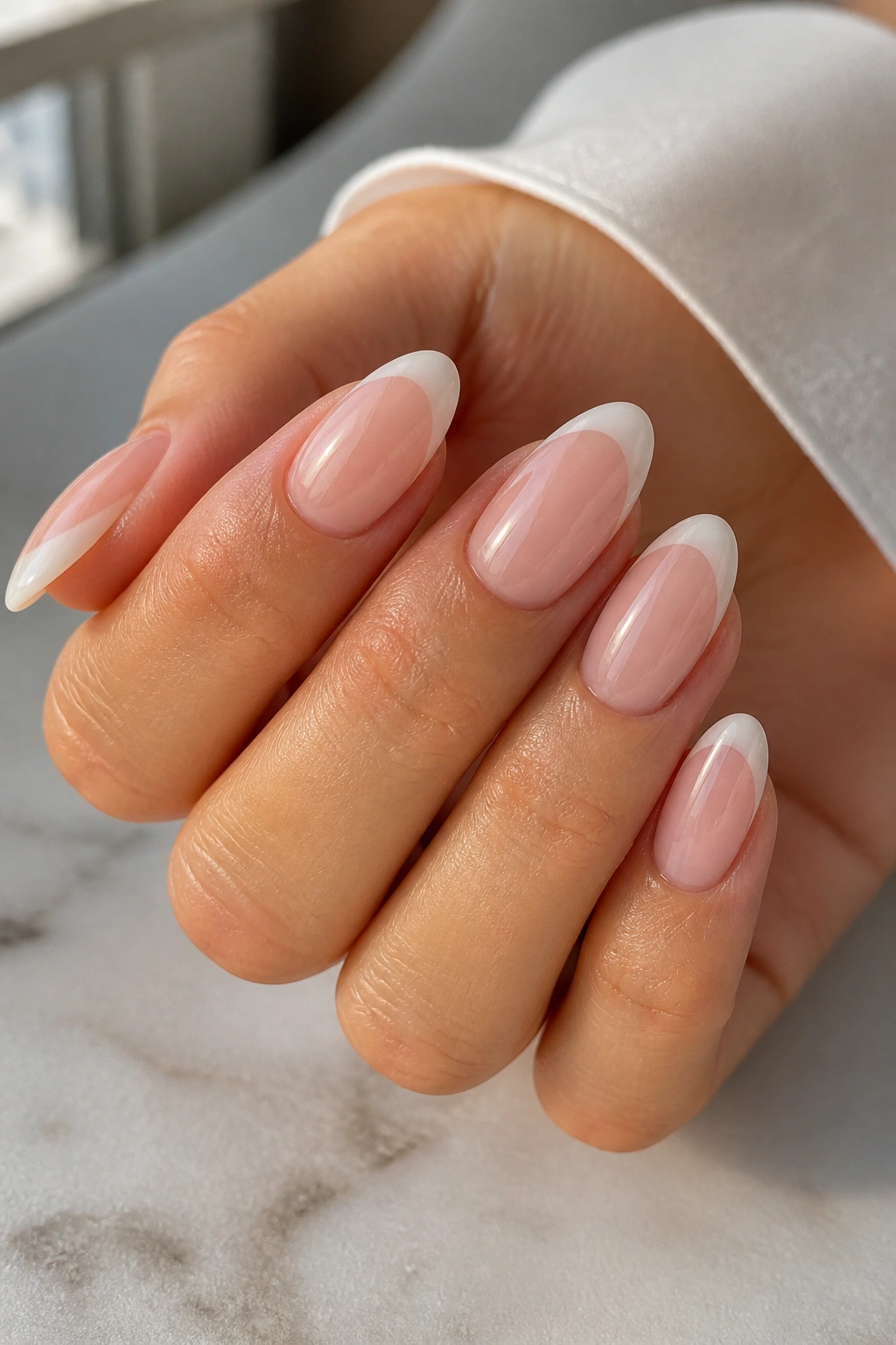Close-up of a real hand with almond nails featuring a soft French ombre smile line.