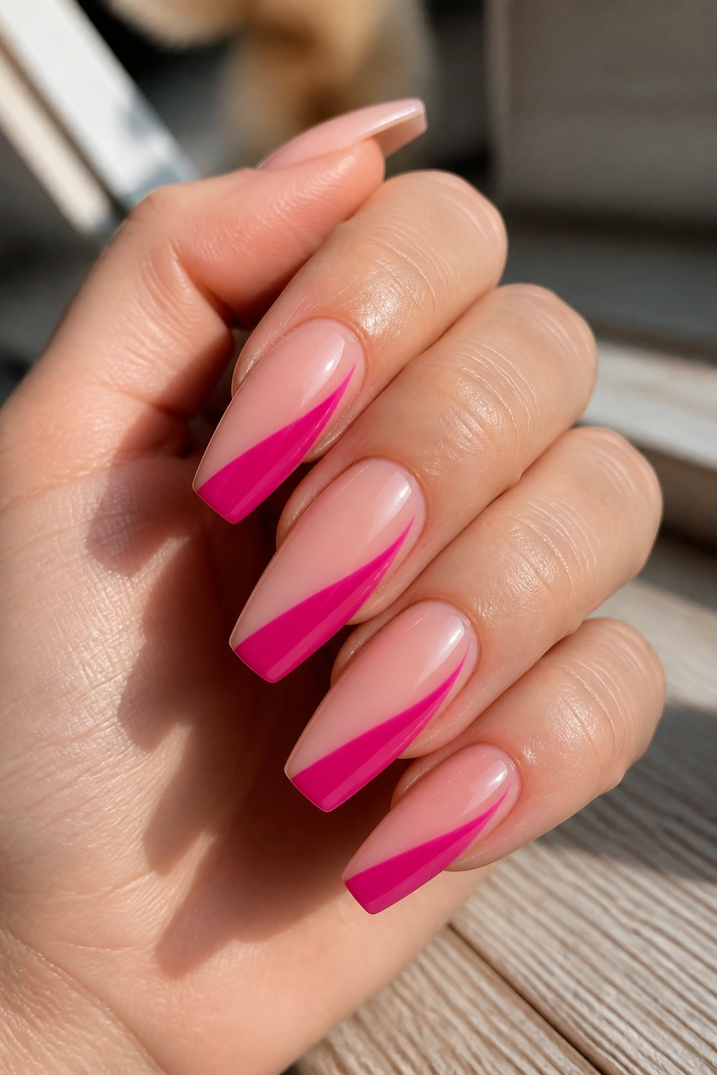 Close-up of nude-pink nails with a fuchsia side-swipe design
