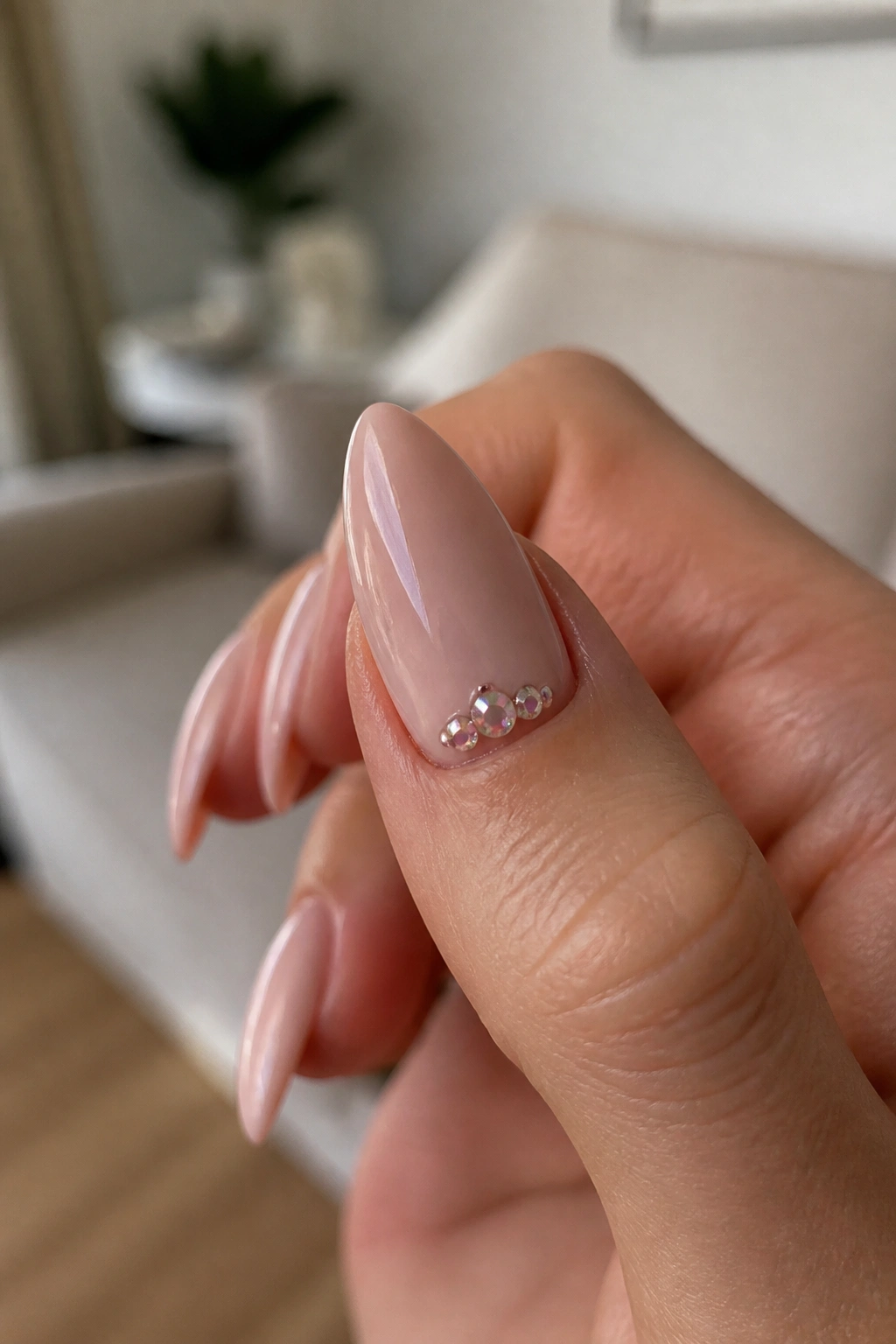 Close-up of almond nail with a gemstone cluster near the cuticle on a real hand.